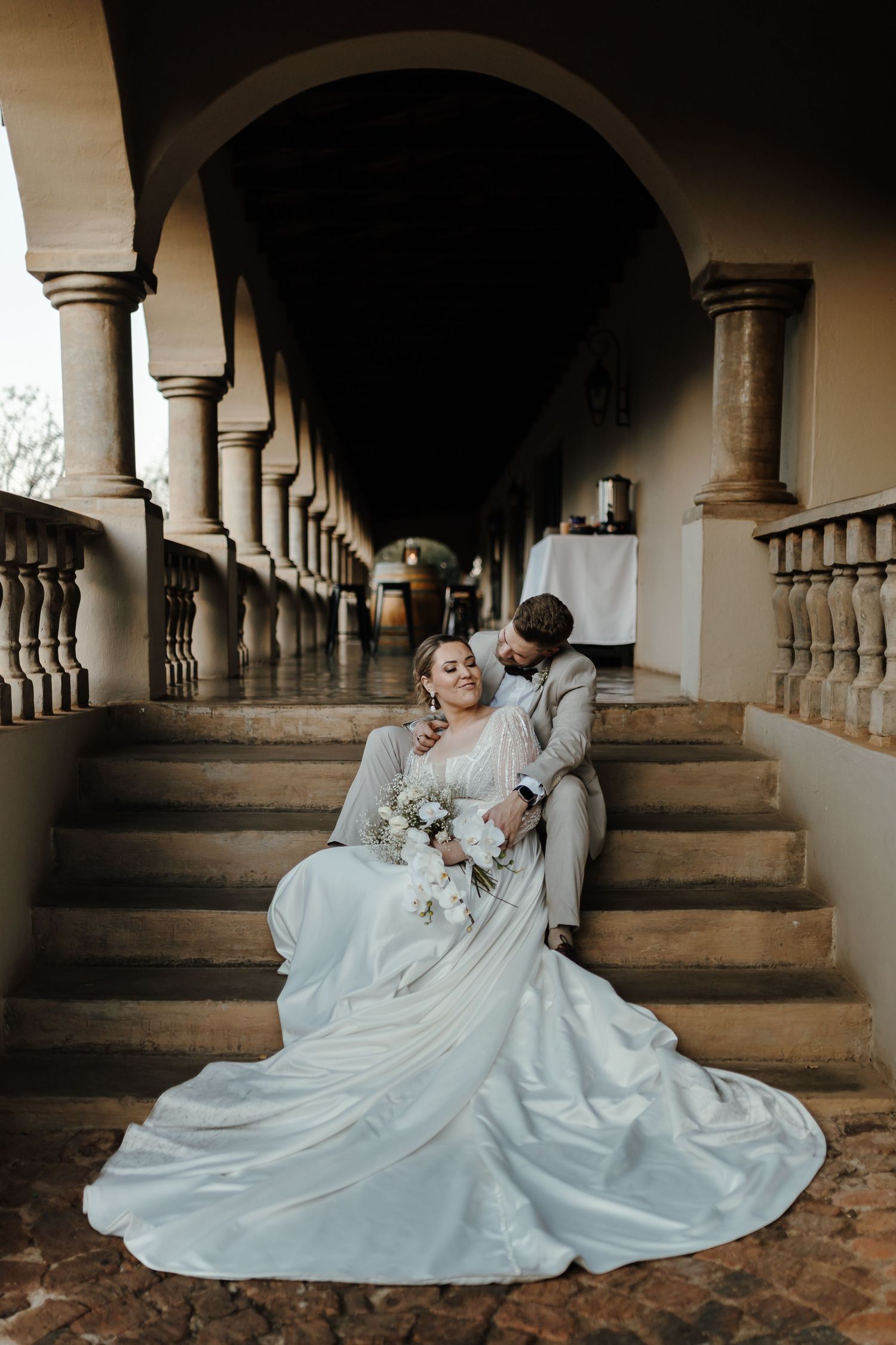 Dramatic wedding portrait on rustic stone steps with ornate archways and columns.