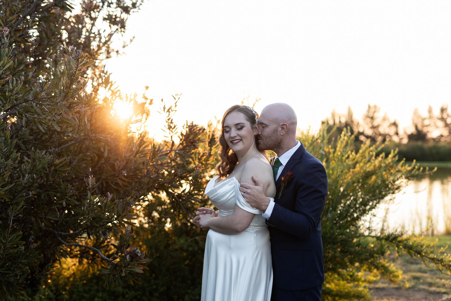 A romantic sunset moment between newlyweds in a garden setting.