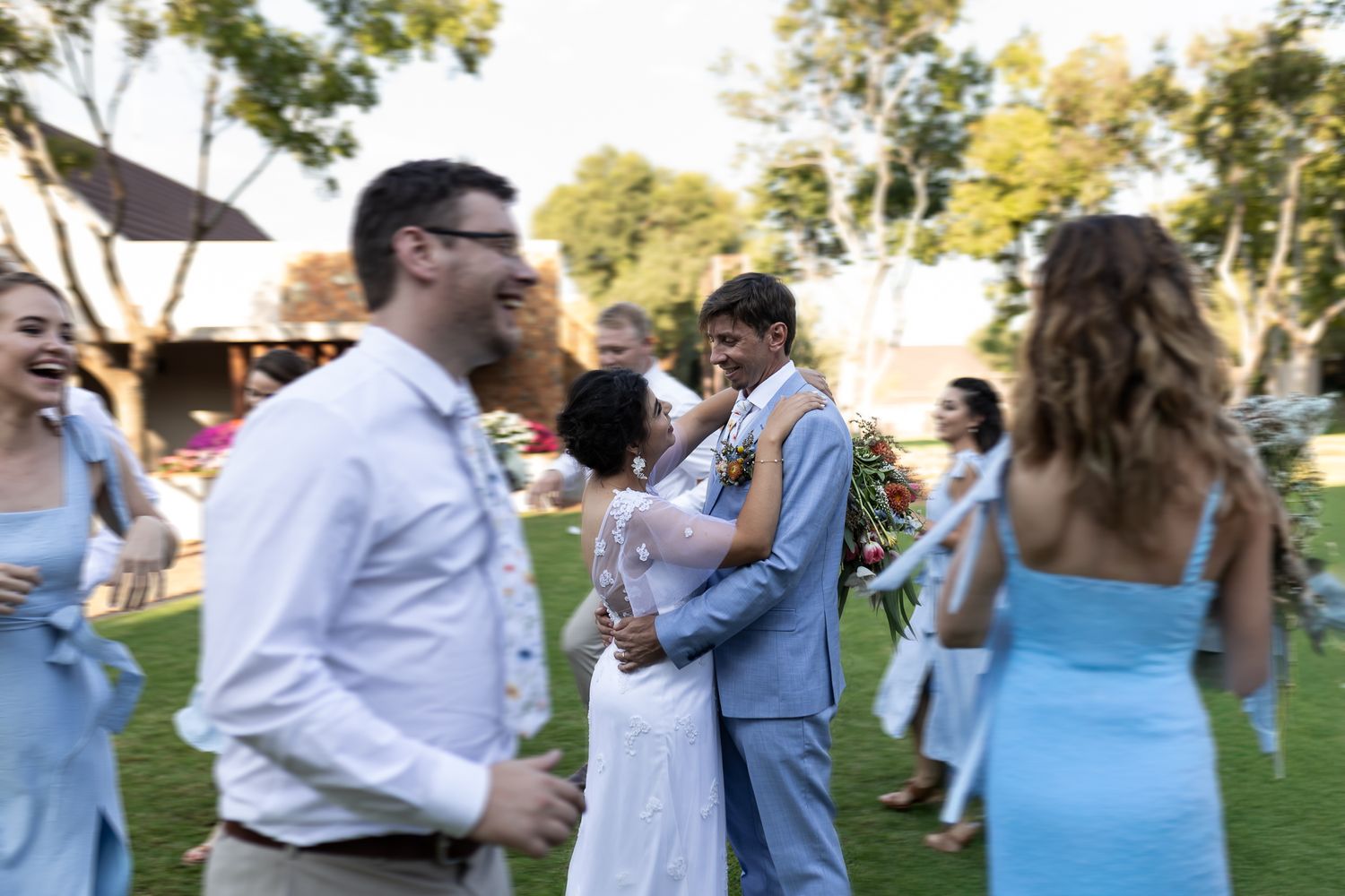 Couples dancing and celebrating at outdoor wedding reception with soft lighting.