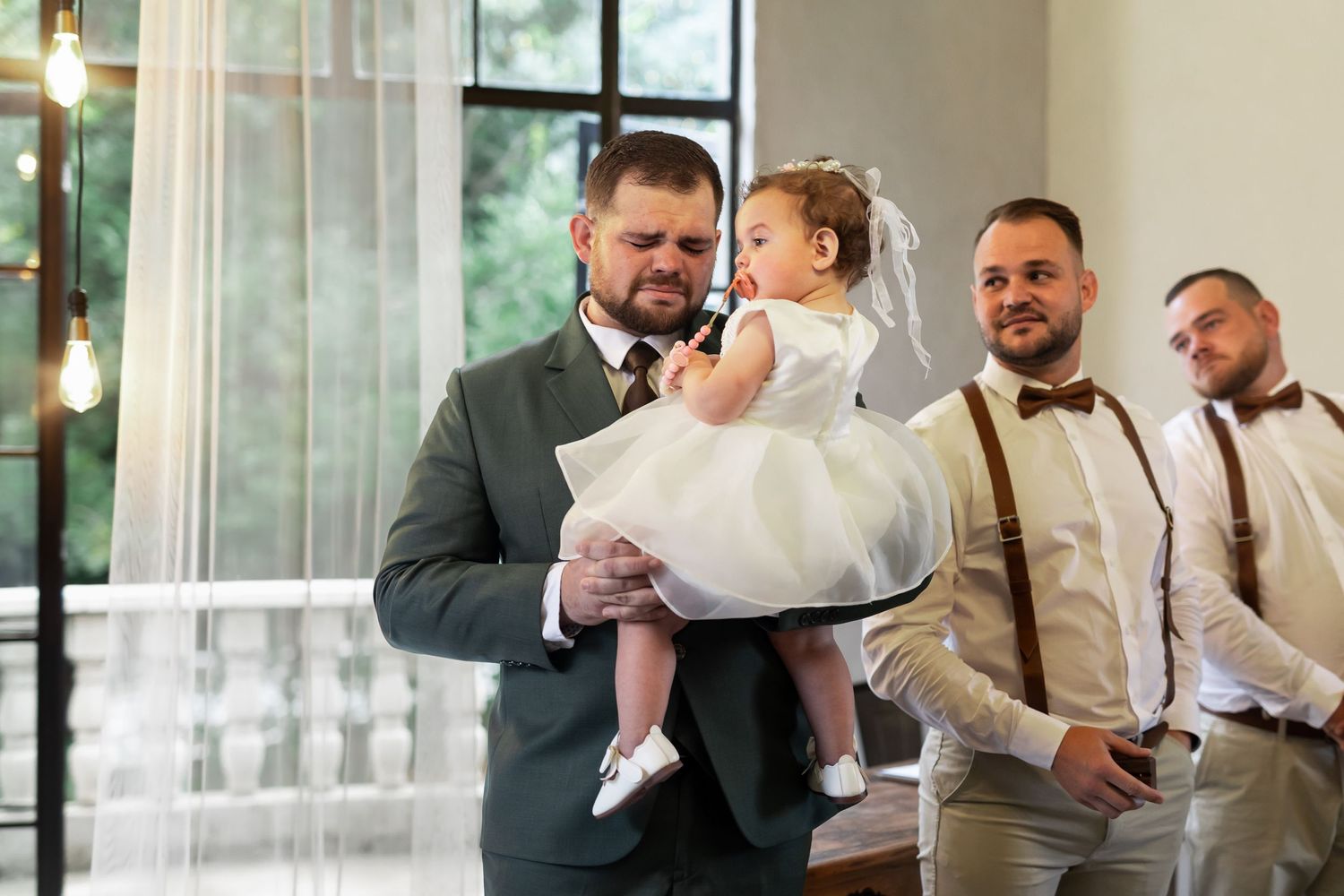 Touching wedding ceremony moment with formal attire and bright interior backdrop.