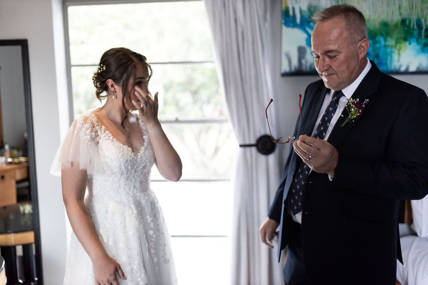 An emotional moment during a wedding ceremony as a bride in a lace dress reacts to a speech being given.