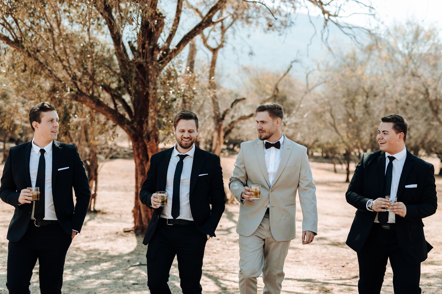 Wedding party in formal attire walks together through desert landscape.
