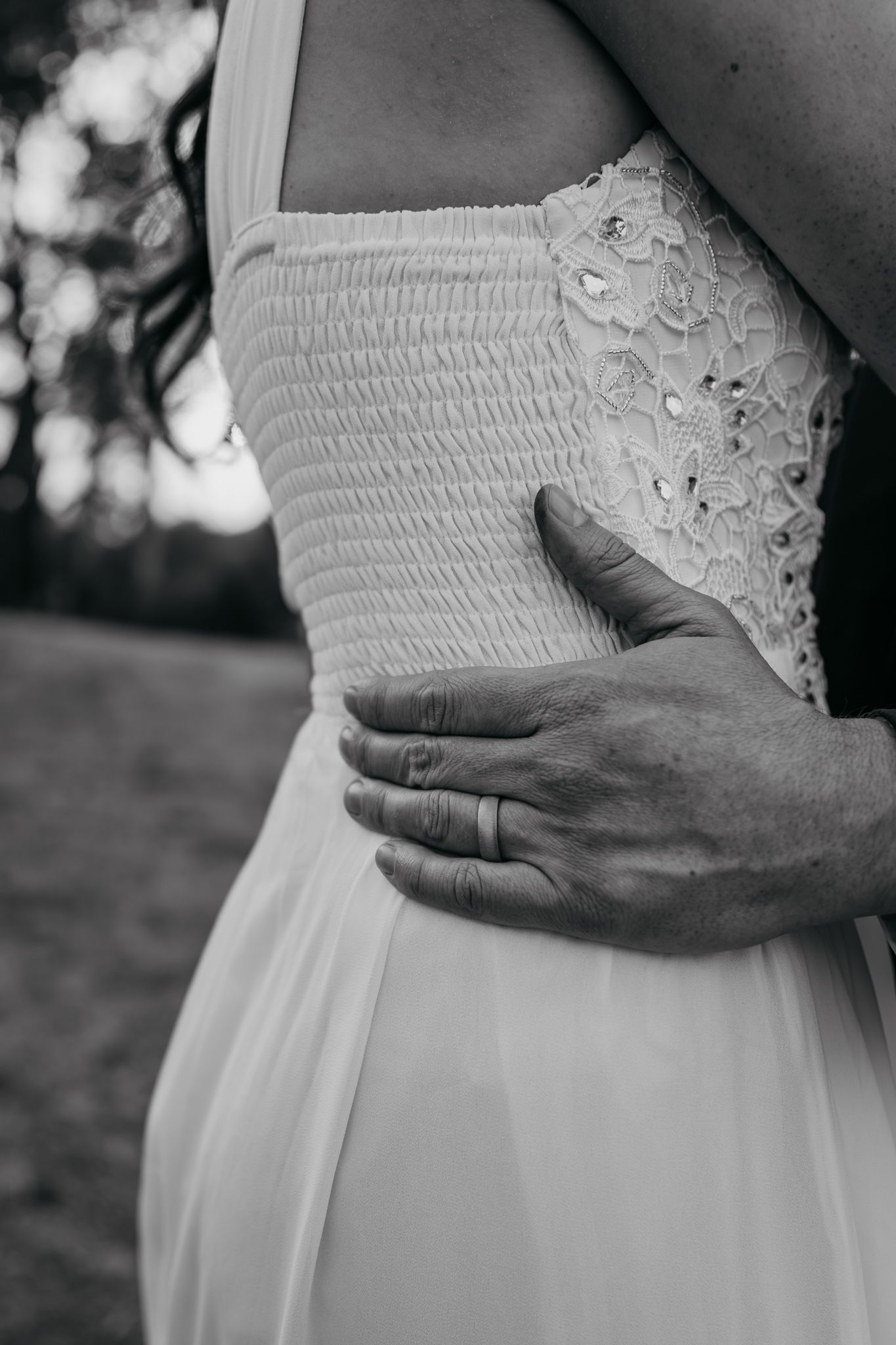 Close-up black and white detail of a wedding dress showing delicate lace and smocking texture.