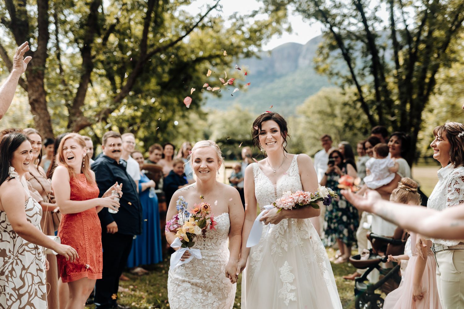Wedding guests cheer and celebrate during an outdoor garden ceremony.