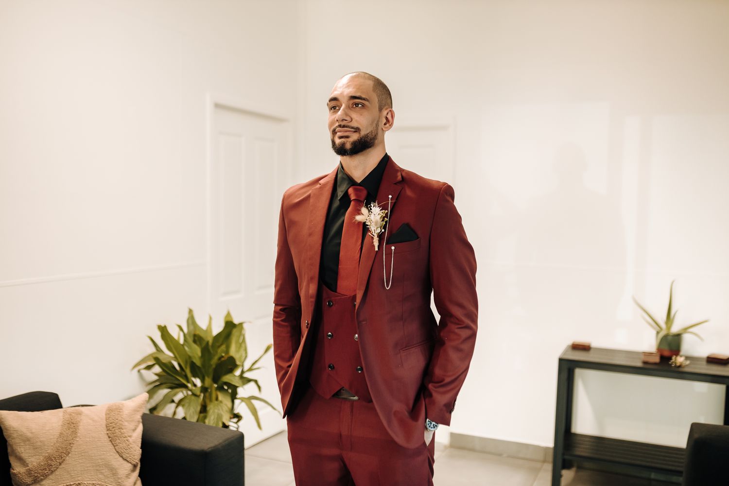 Person wearing burgundy suit standing in modern minimalist interior.