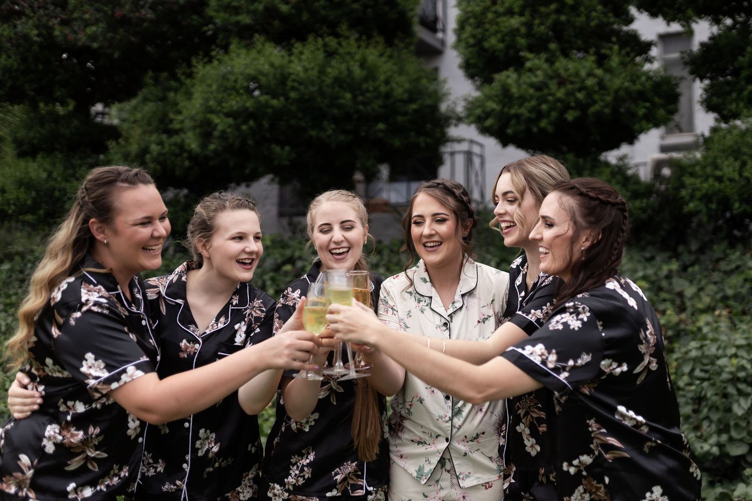 Friends raise glasses in celebratory toast outdoors.