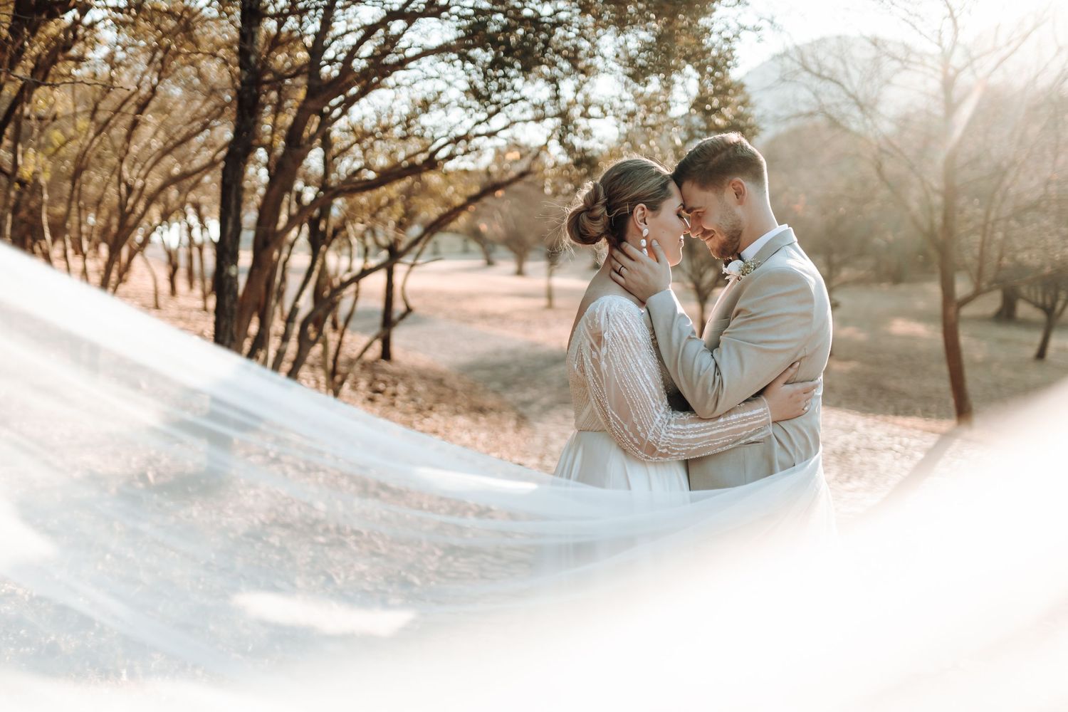 Artistic wedding portrait with ethereal veil movement in autumn outdoor setting.