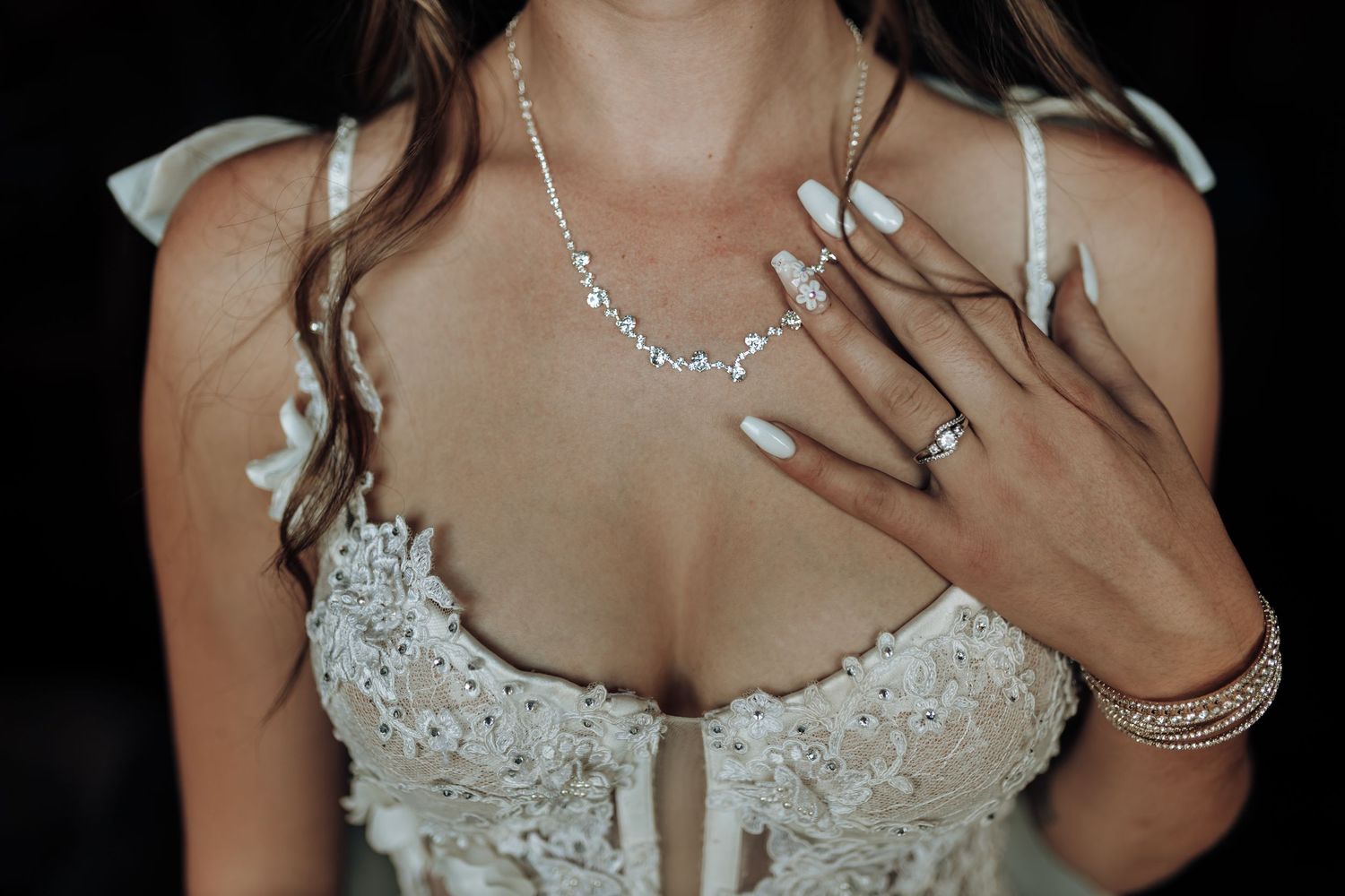 Detail shot of bridal jewelry and lace bodice with delicate embellishments.