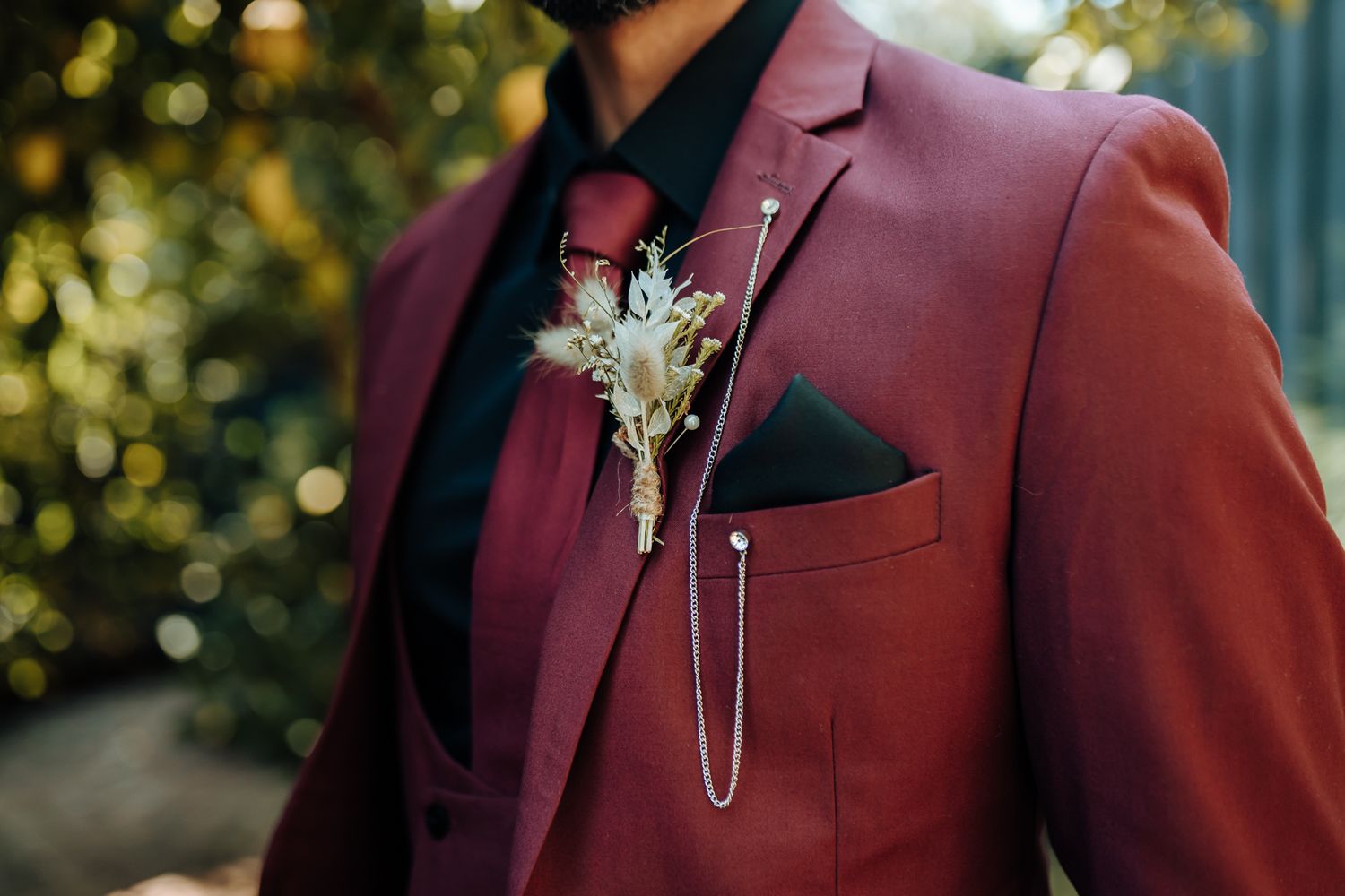 Close-up of burgundy suit lapel with elegant crystal boutonniere.