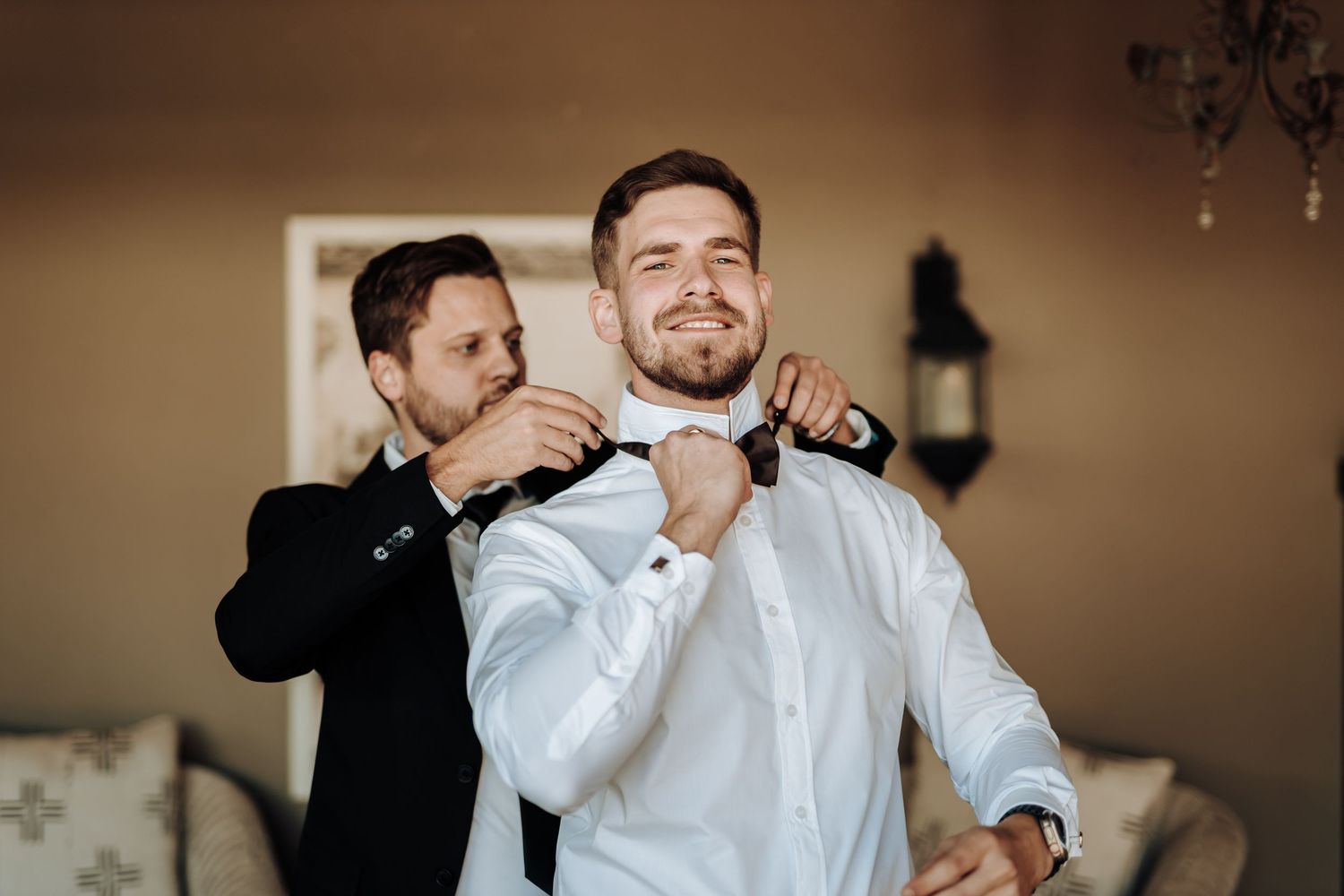 Getting ready moment as bow tie is adjusted in formal attire.