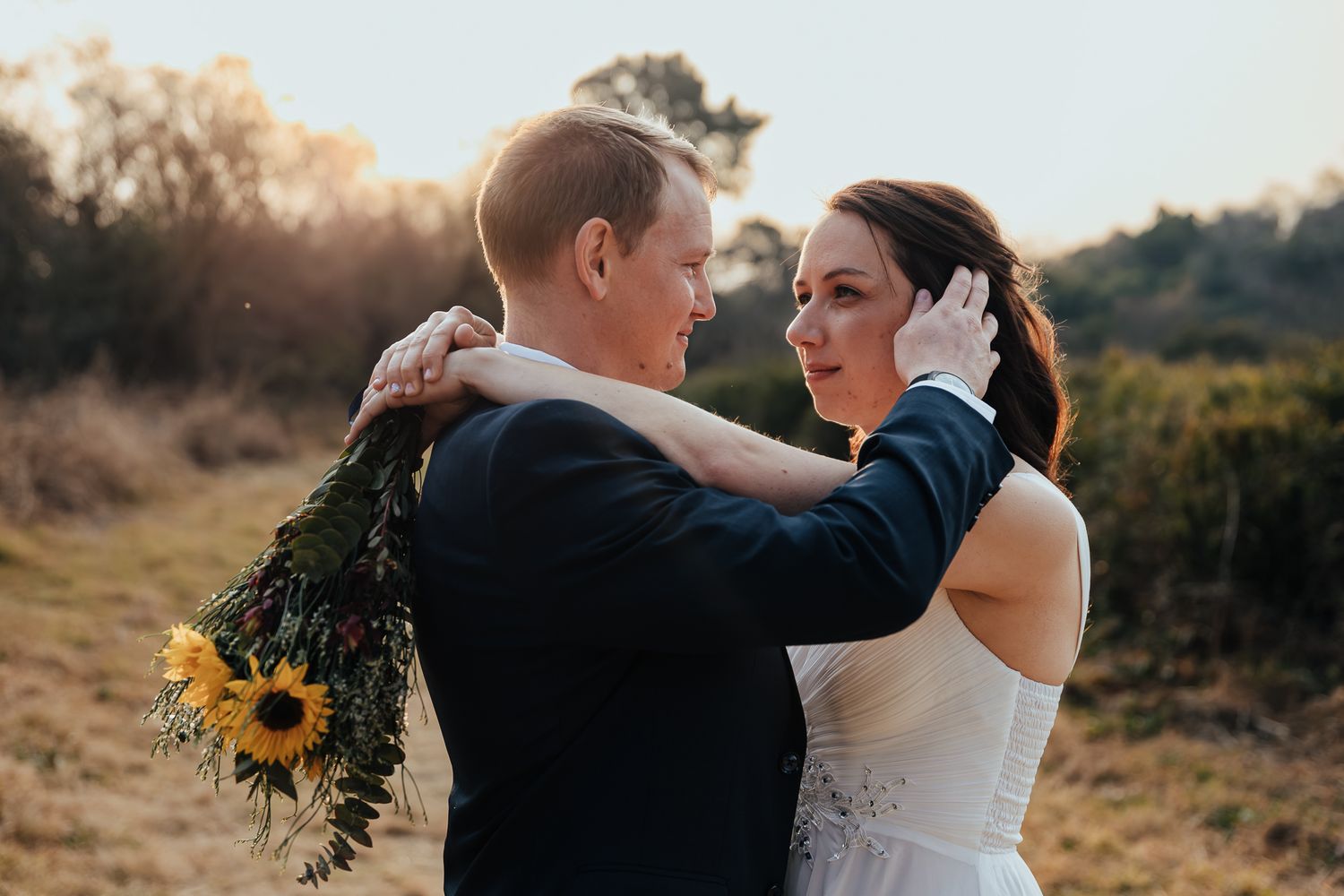 Couple shares romantic dance at sunset with sunflowers adding golden warmth to their wedding celebration.