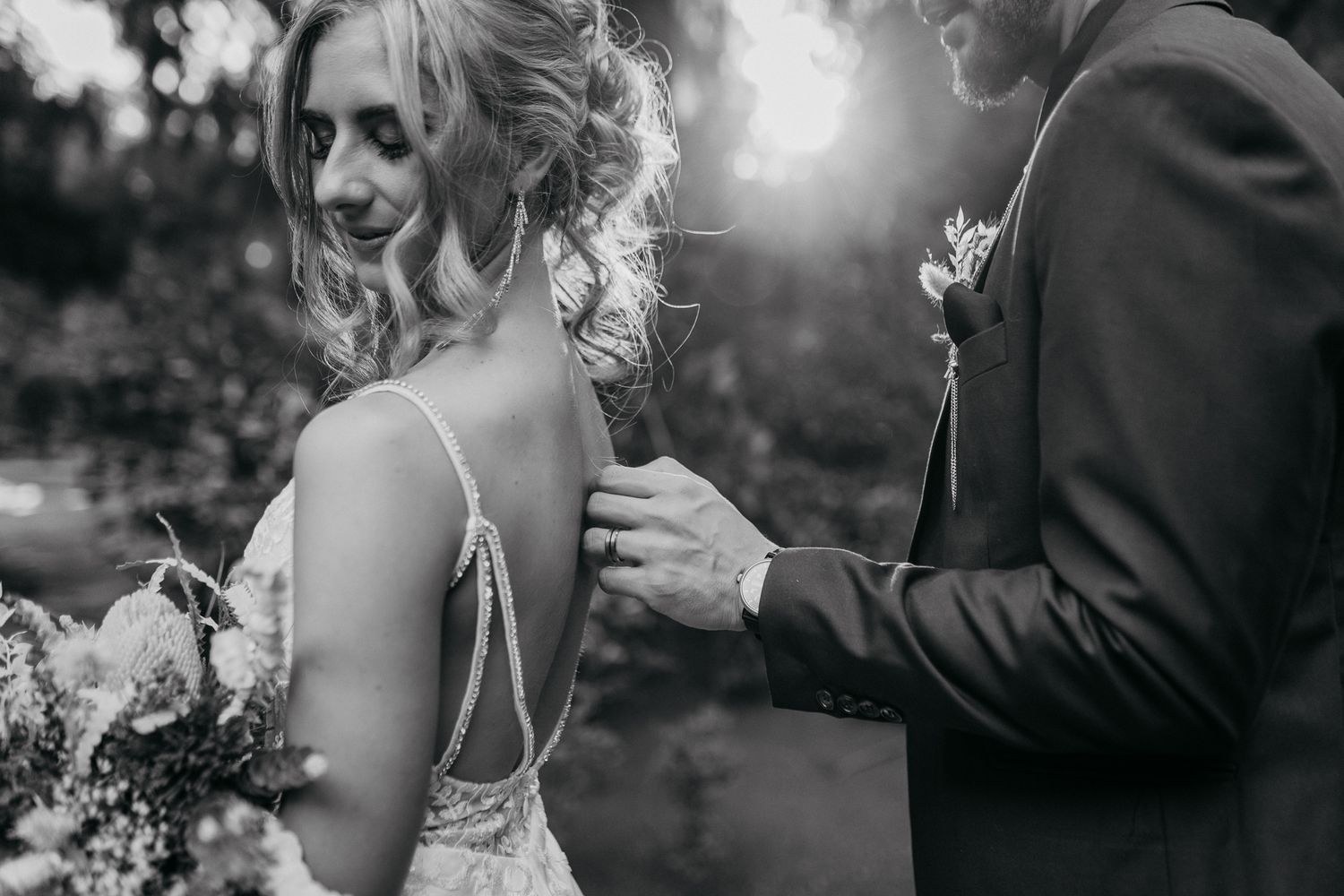 Black and white photo showing delicate details of a bride's wedding dress and hairstyle.