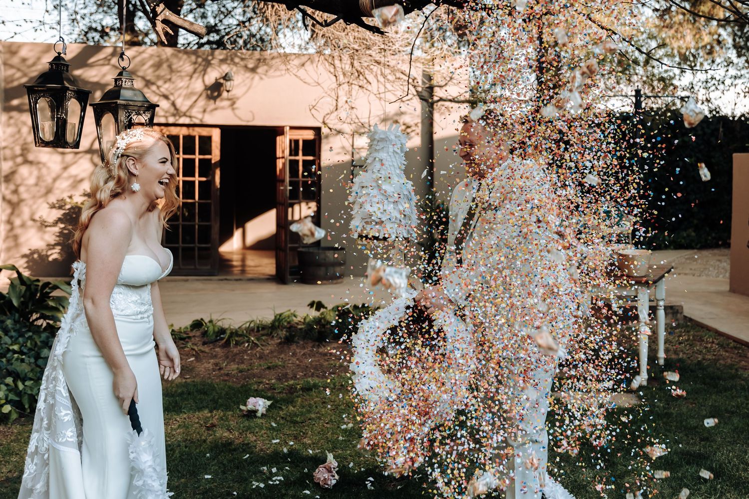 Wedding couple pops champagne in an outdoor garden celebration creating a festive spray.