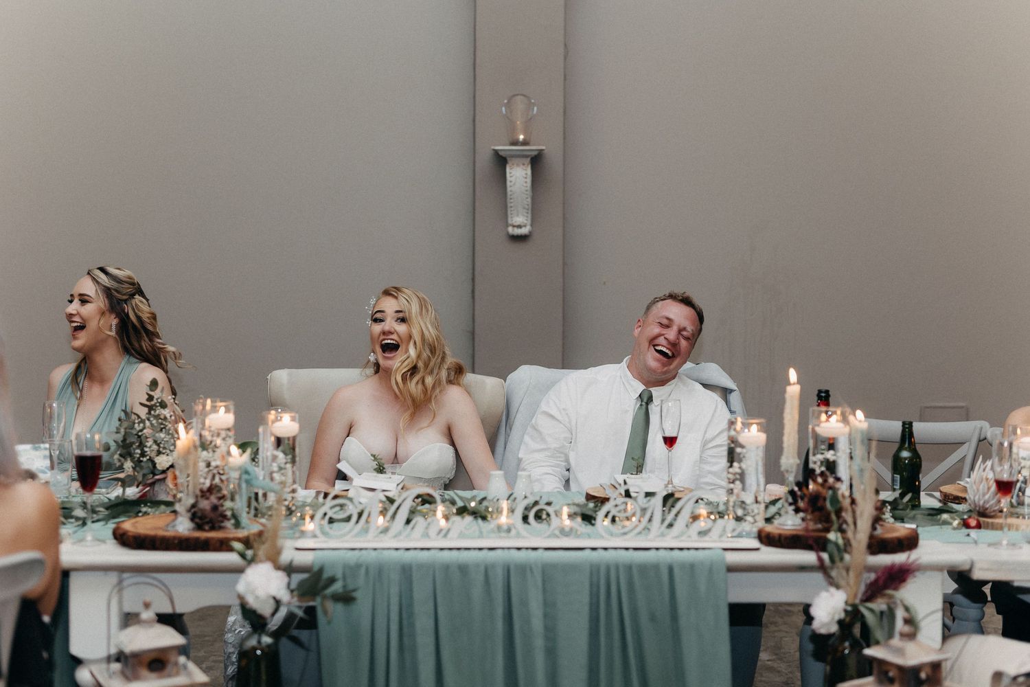 Reception table adorned with mint green linens, candles and natural greenery.