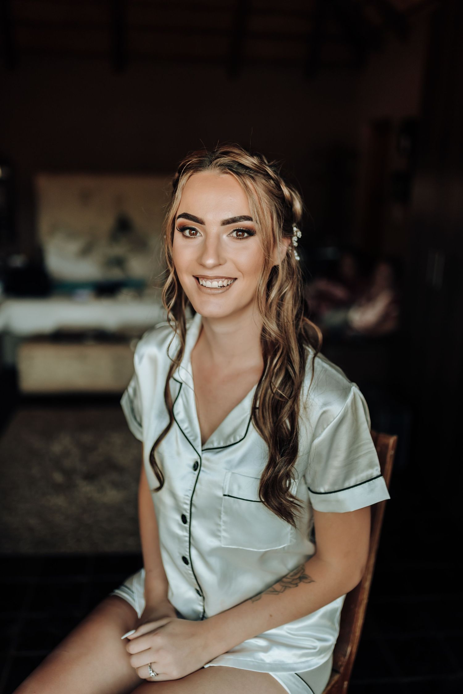 Portrait of someone wearing a light blue silk pajama set while sitting and smiling.