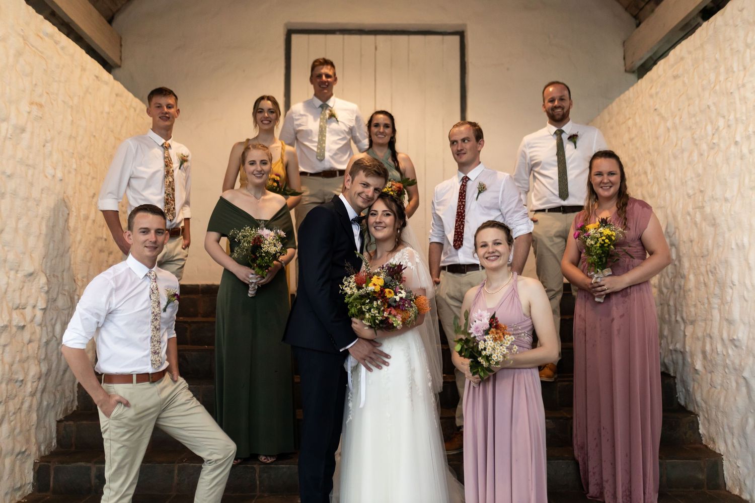 Fun wedding party portrait with casual poses in front of a minimalist doorway.