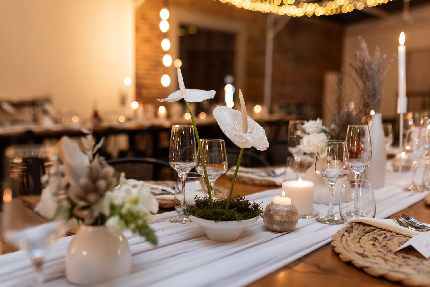Intimate wedding table setting with white linens, candles and delicate floral arrangements.