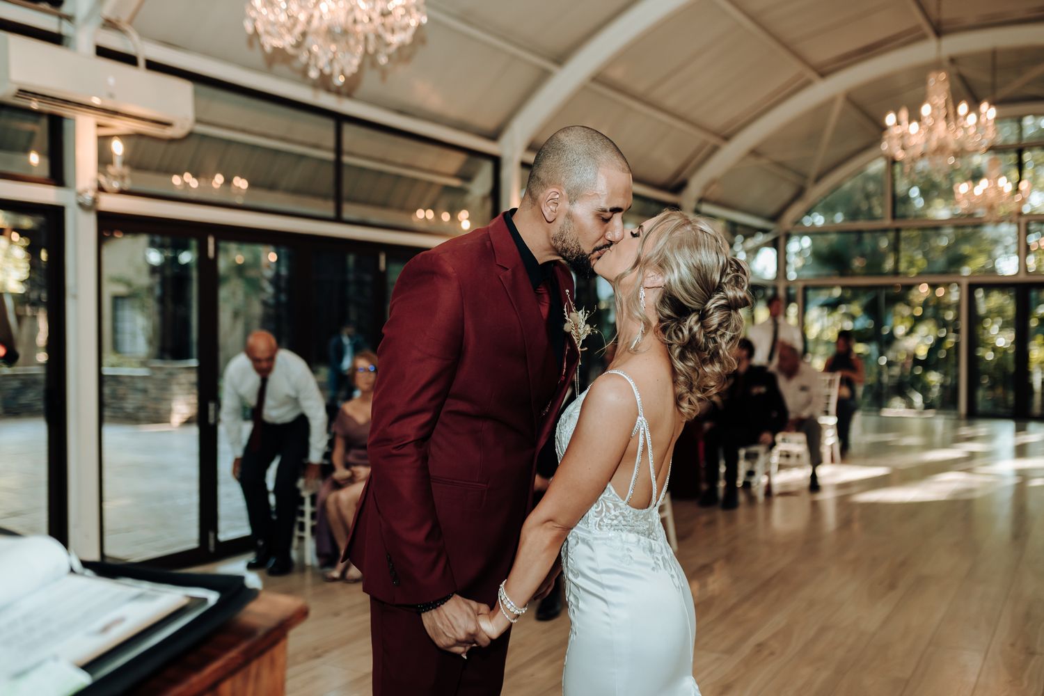 Intimate wedding ceremony moment in a sunlit venue with elegant chandeliers.