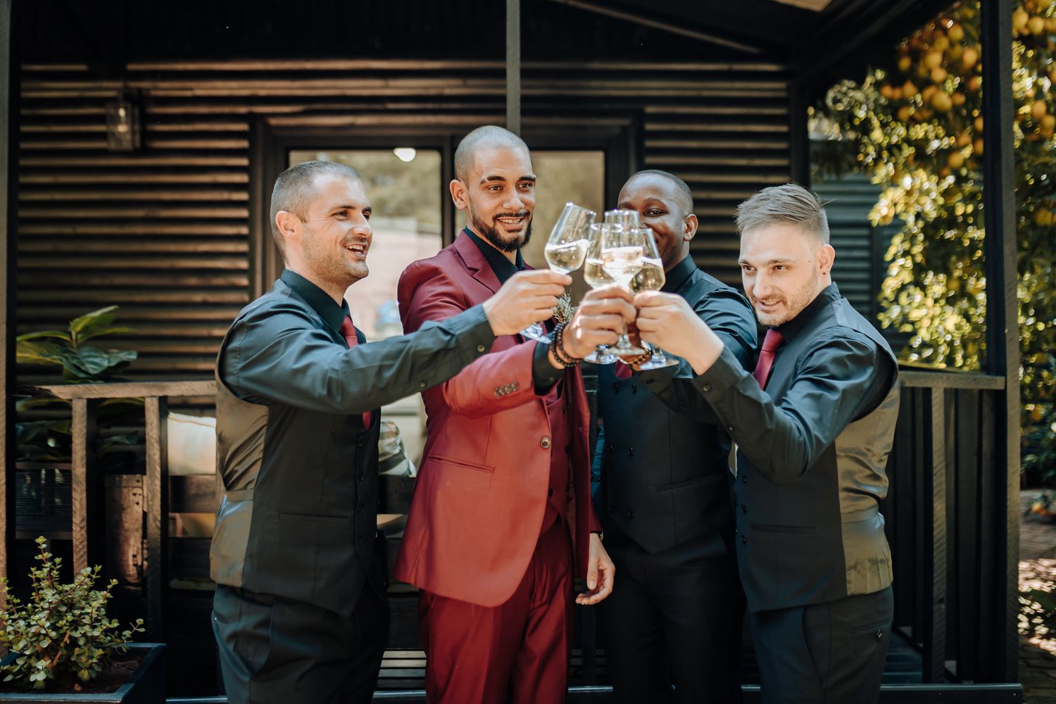 Wedding party raising glasses in a celebratory toast outside.