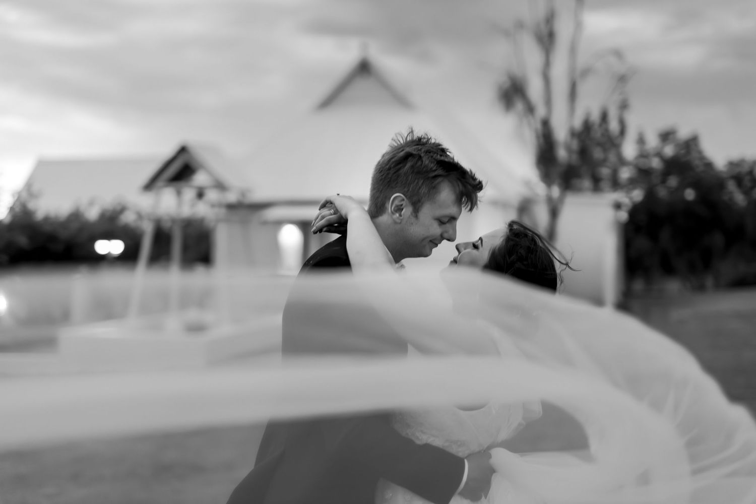 Romantic black and white portrait with flowing veil creating dreamy effect.
