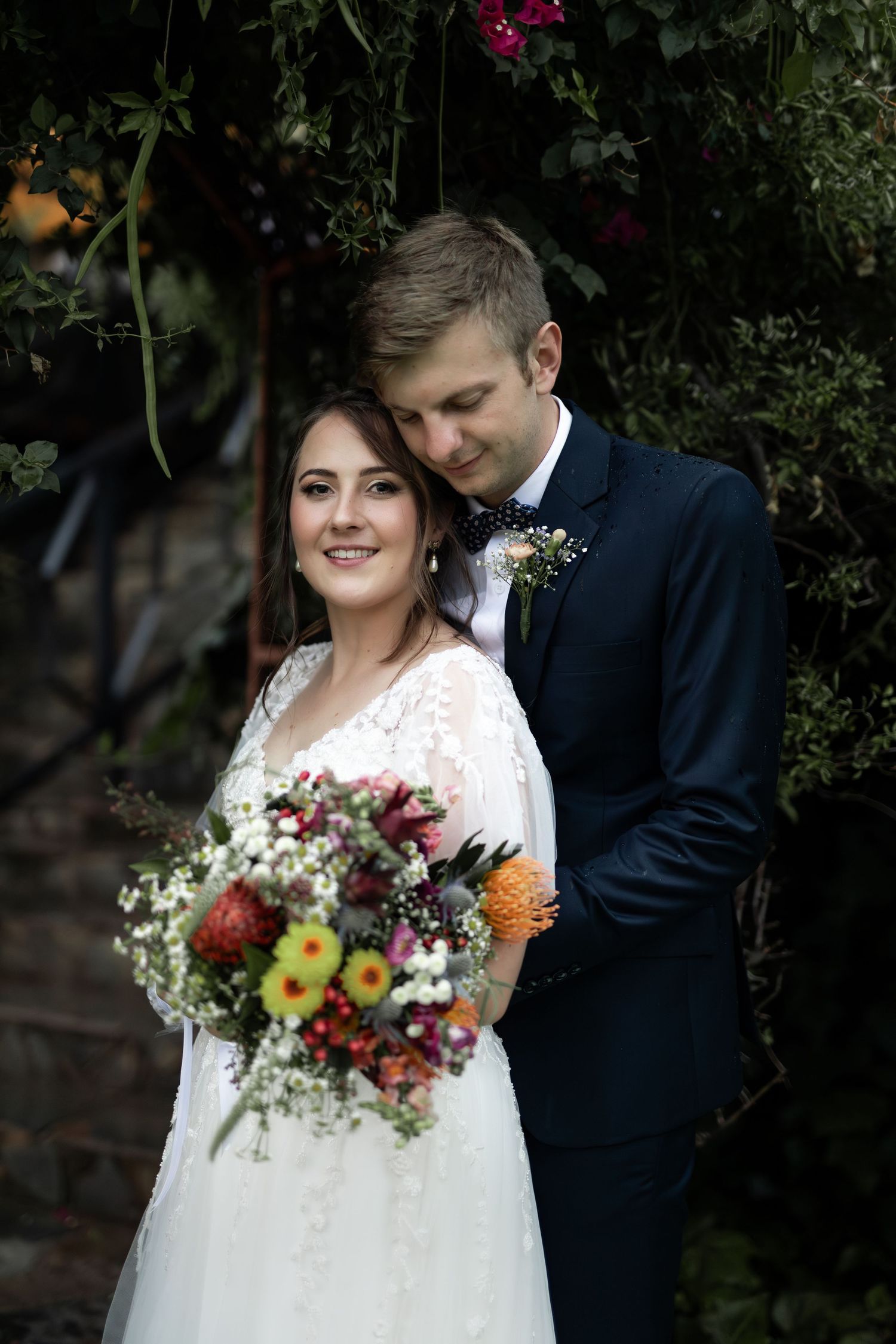 Wedding portrait with vibrant wildflower bouquet against garden backdrop.