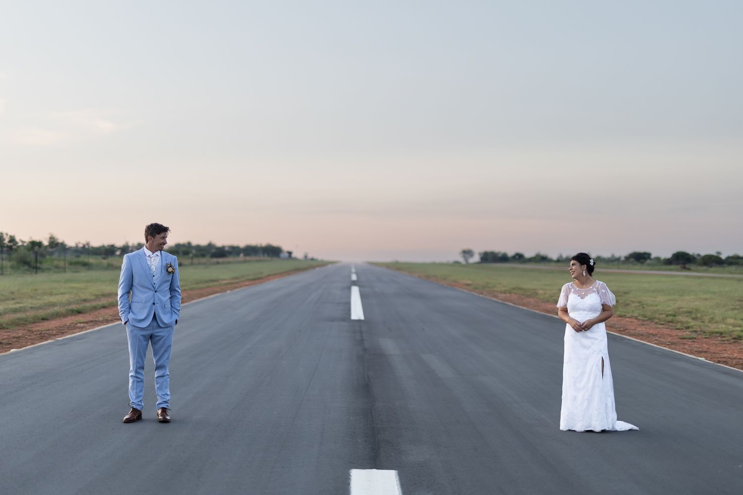 Wedding couple standing at opposite ends of empty runway.
