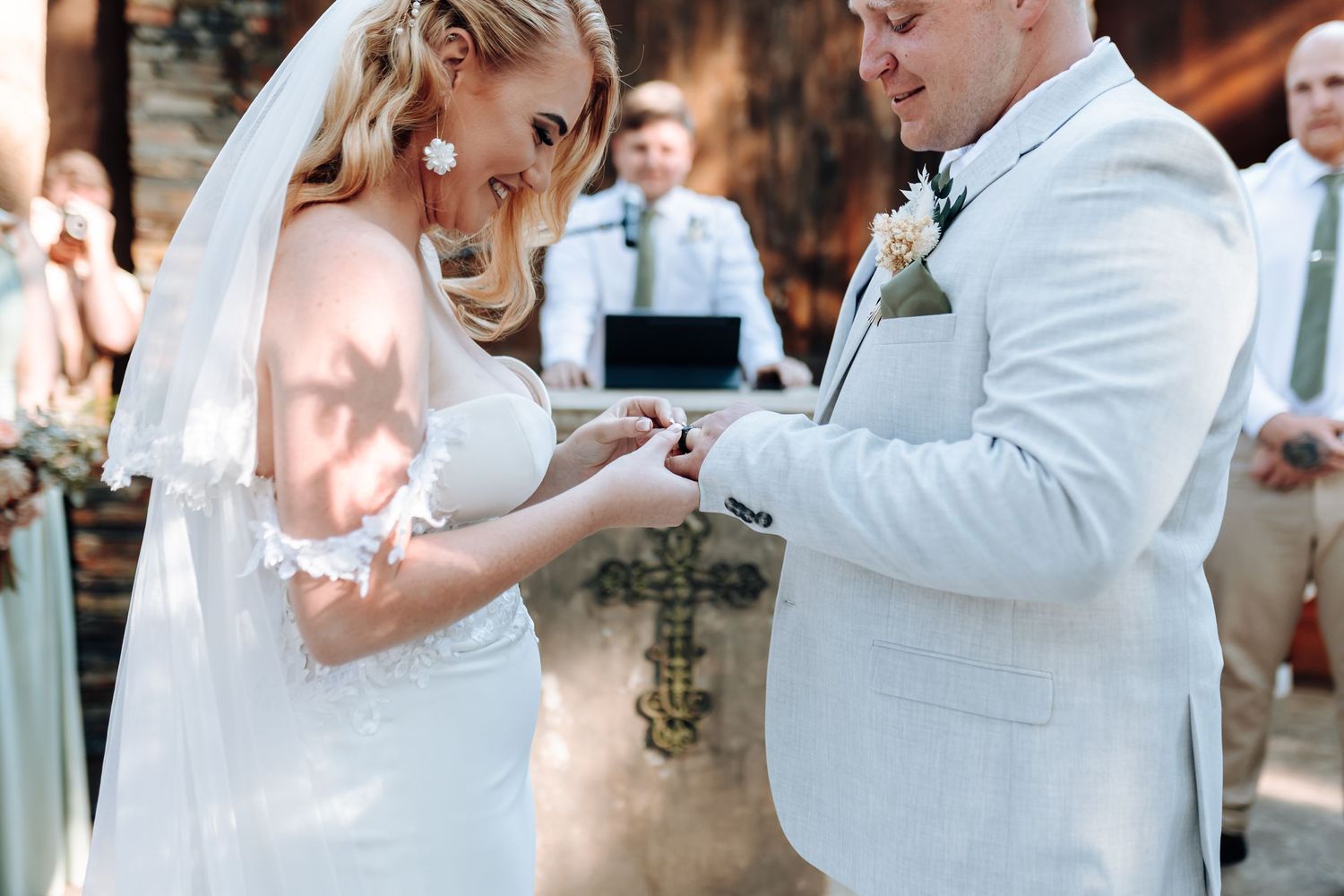 Couple exchanging rings during intimate forest wedding ceremony.