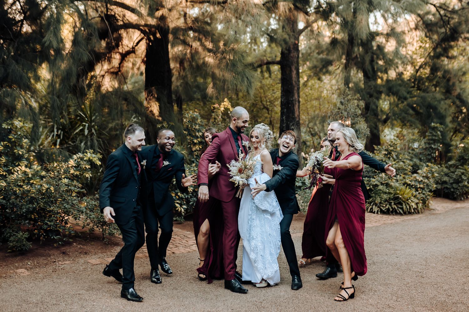 Wedding party dances and celebrates together on outdoor path.