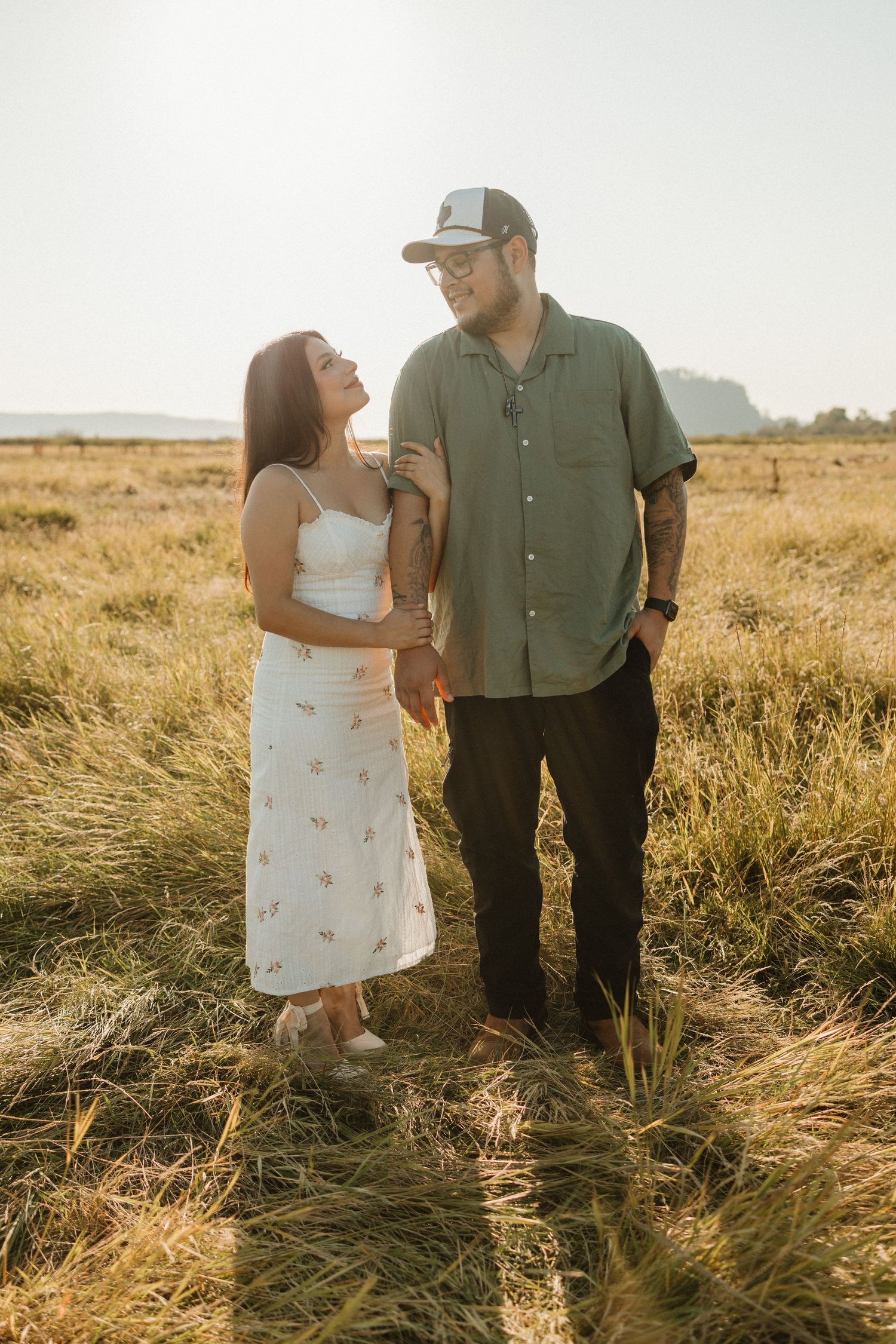 Romantic couple standing together in a golden wheat field during sunset.