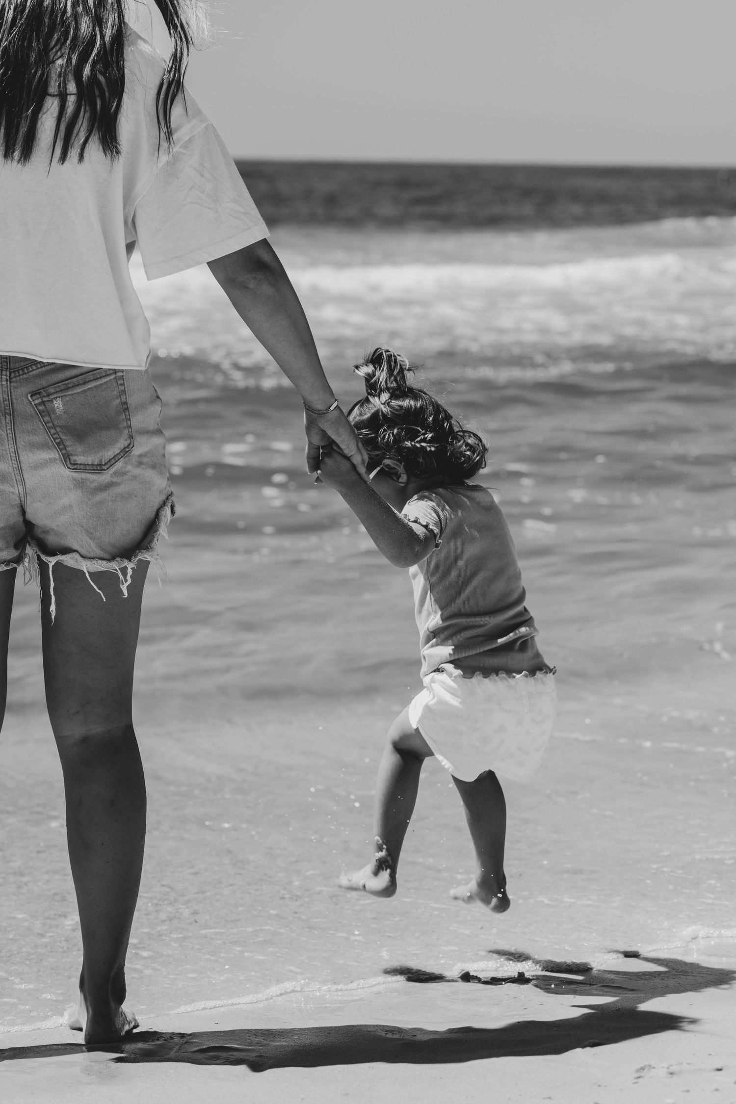 A sequence of cascading black and white photos showing legs and feet walking along a sandy beach shoreline.