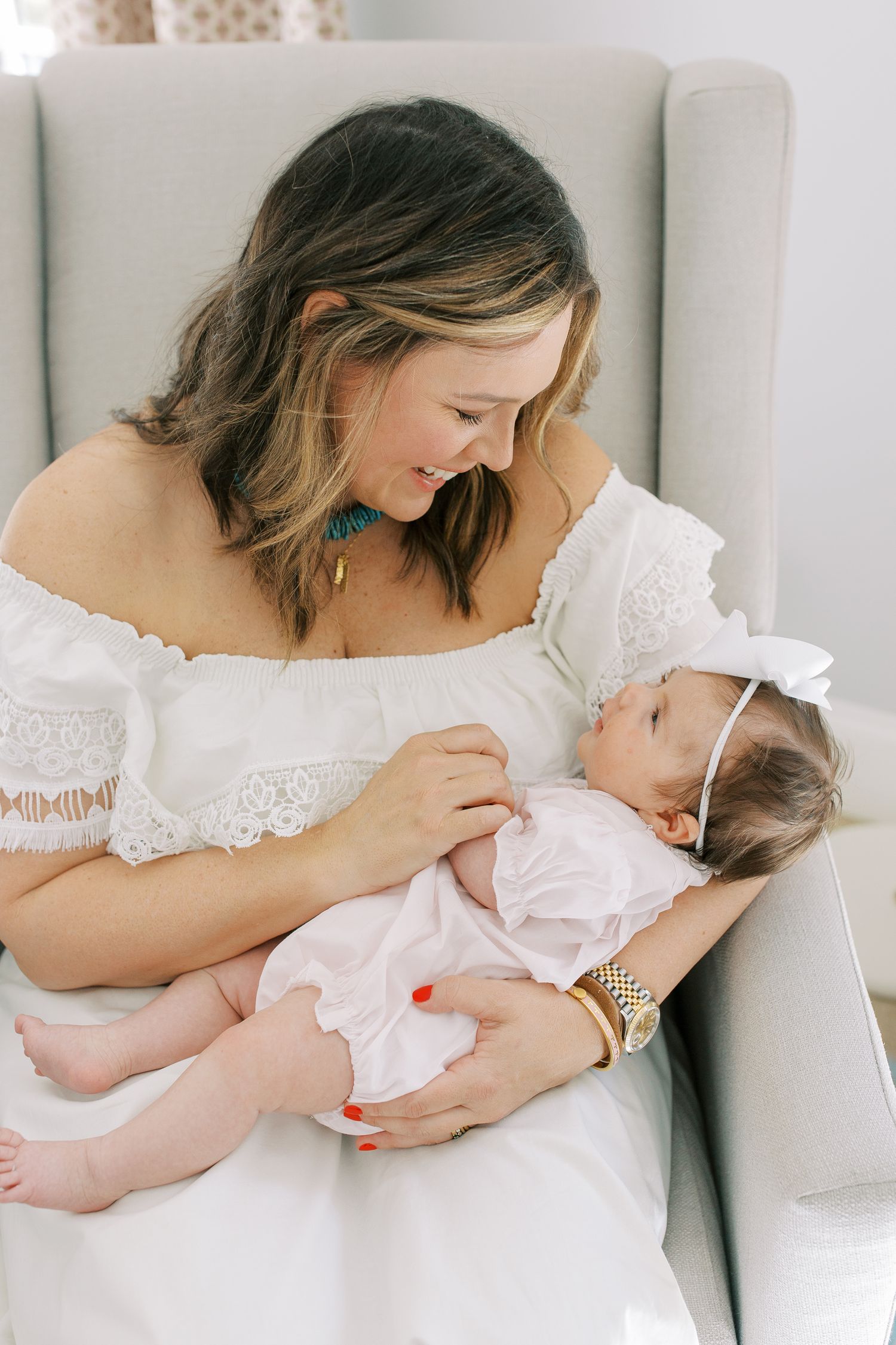 Sweet tender moment in a white armchair with gentle lighting and soft textures.