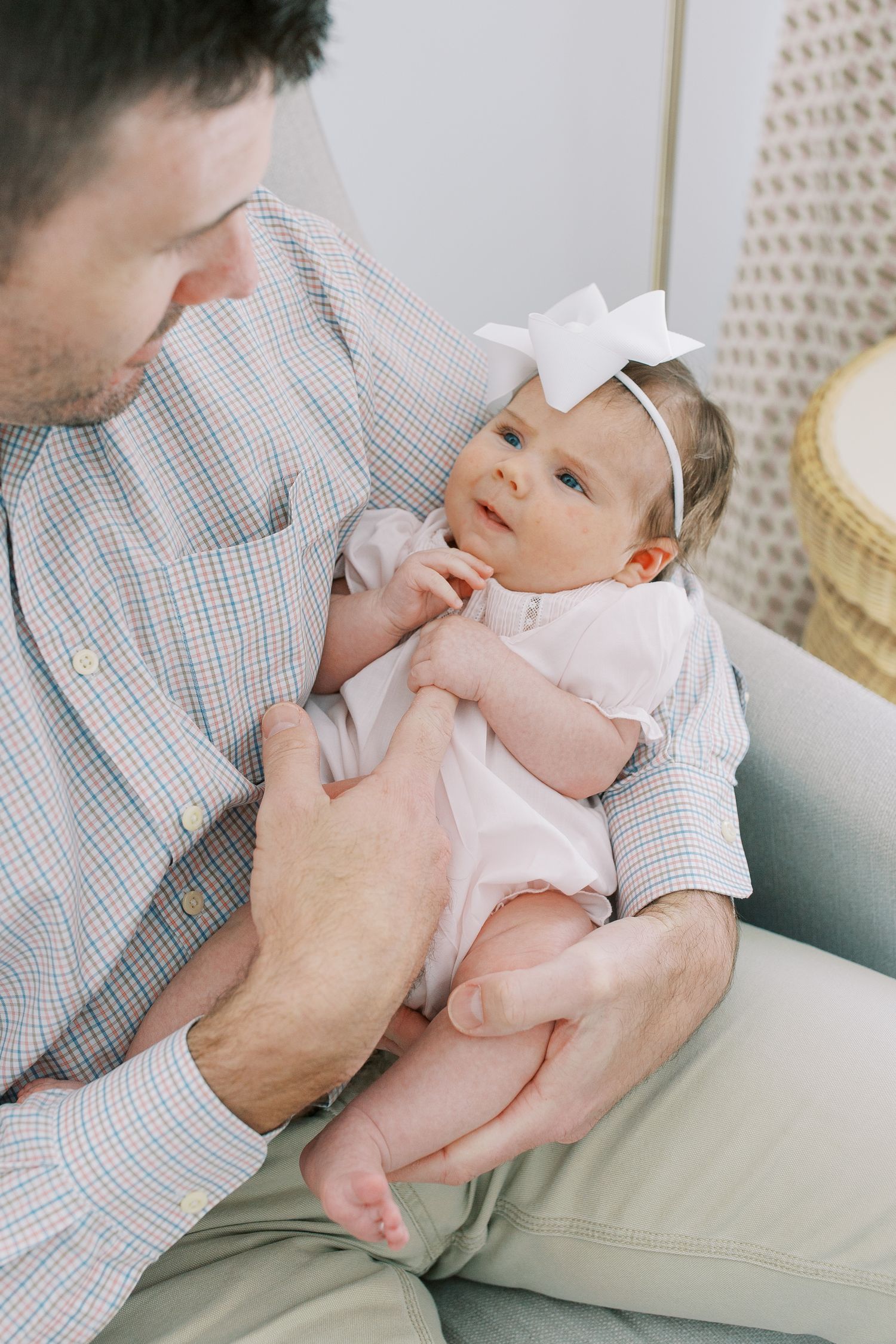 Tender moment between parent and baby in light-filled room with woven decor.