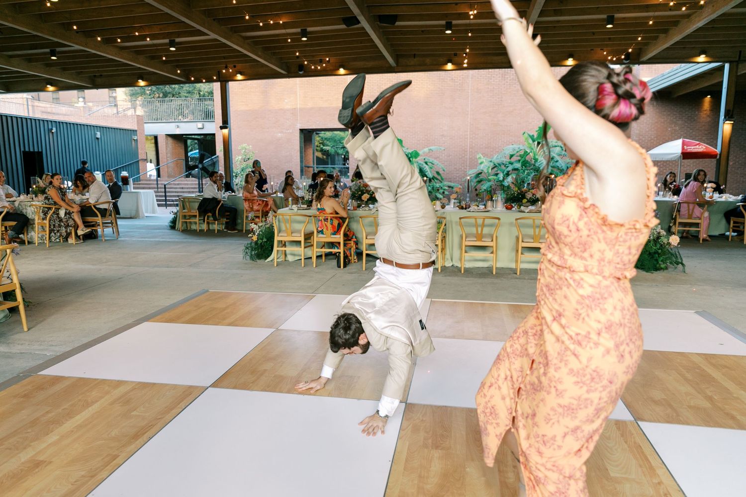 Wedding reception dancers show off energetic moves on checkered dance floor.