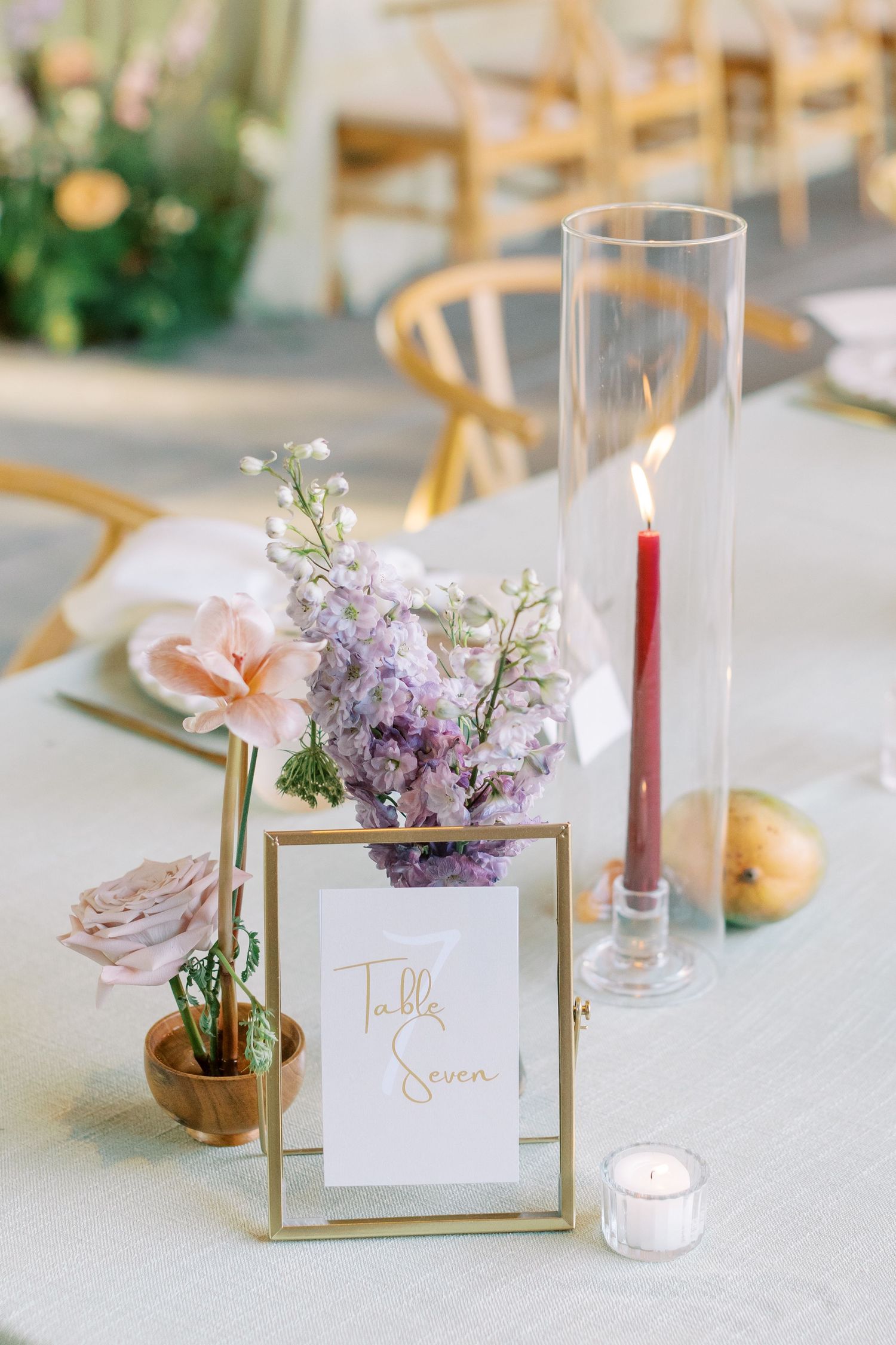 Elegant table settings with purple flowers, candles and gold-framed place cards.