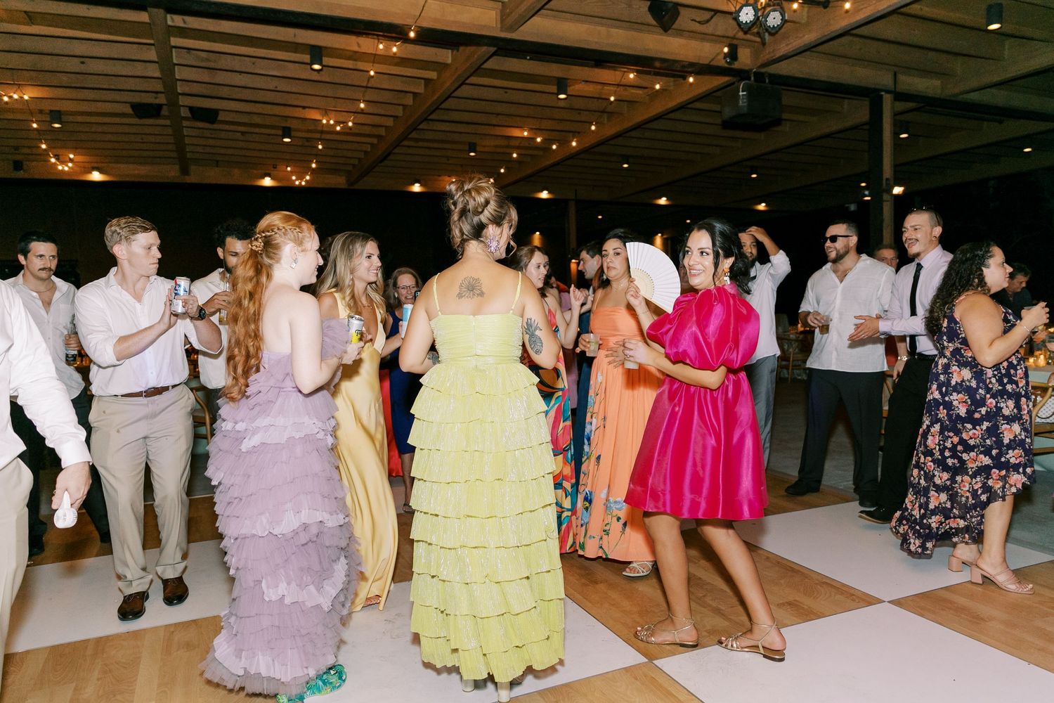 Wedding reception dance floor filled with guests in colorful dresses enjoying the celebration.