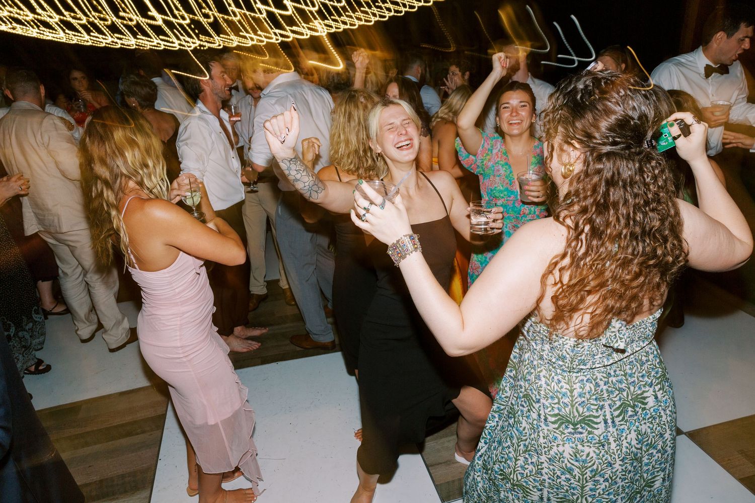 Wedding reception dance party with guests enjoying themselves under string lights.
