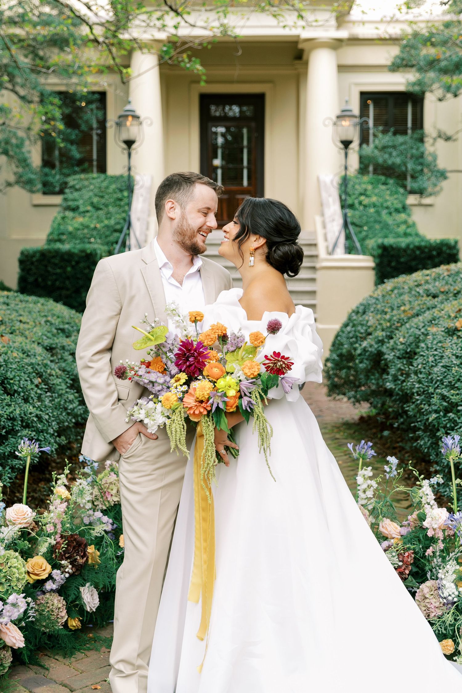 A bride and groom share an intimate moment in a garden with colorful wedding bouquet.