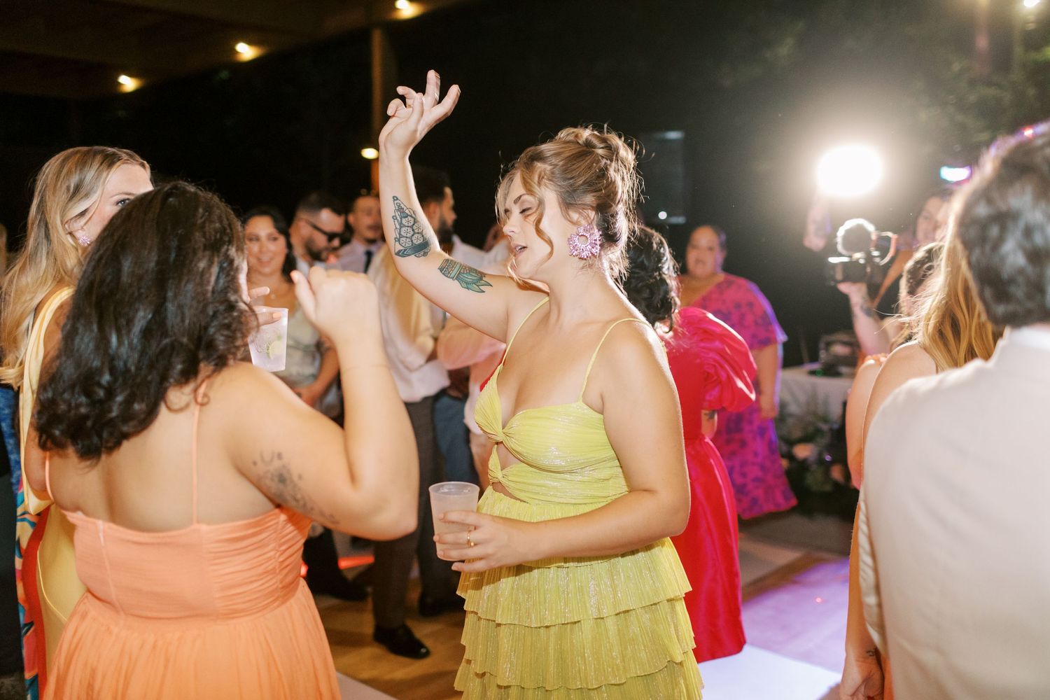 Wedding guests dancing and celebrating together on a dimly lit dance floor.