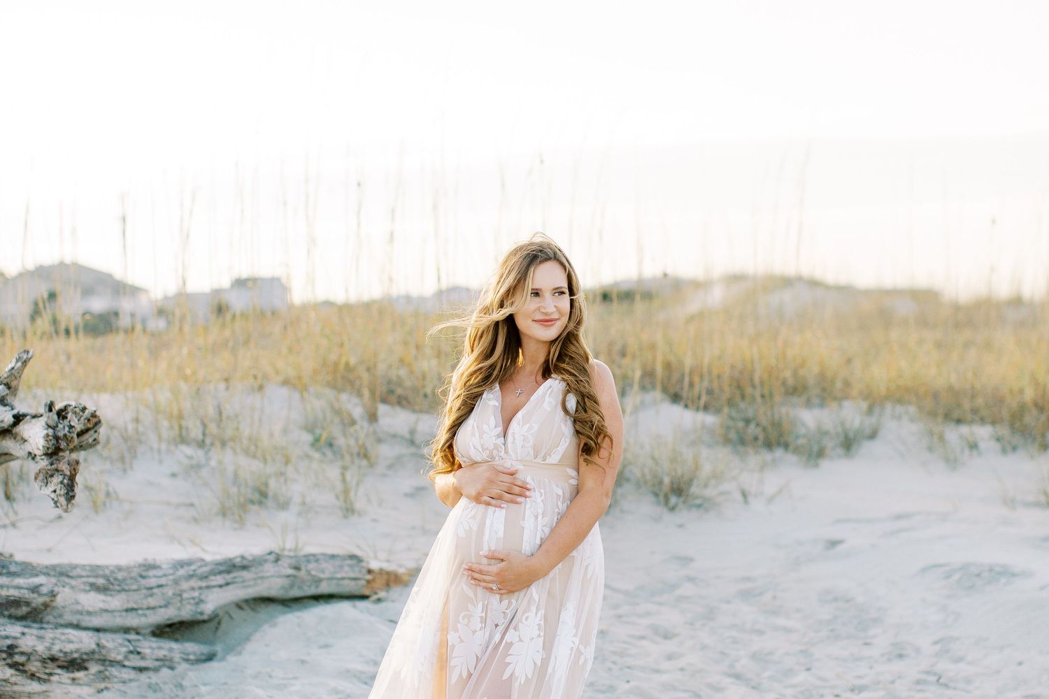 A romantic beach photo session featuring white flowing dresses against sand dunes and soft natural lighting.