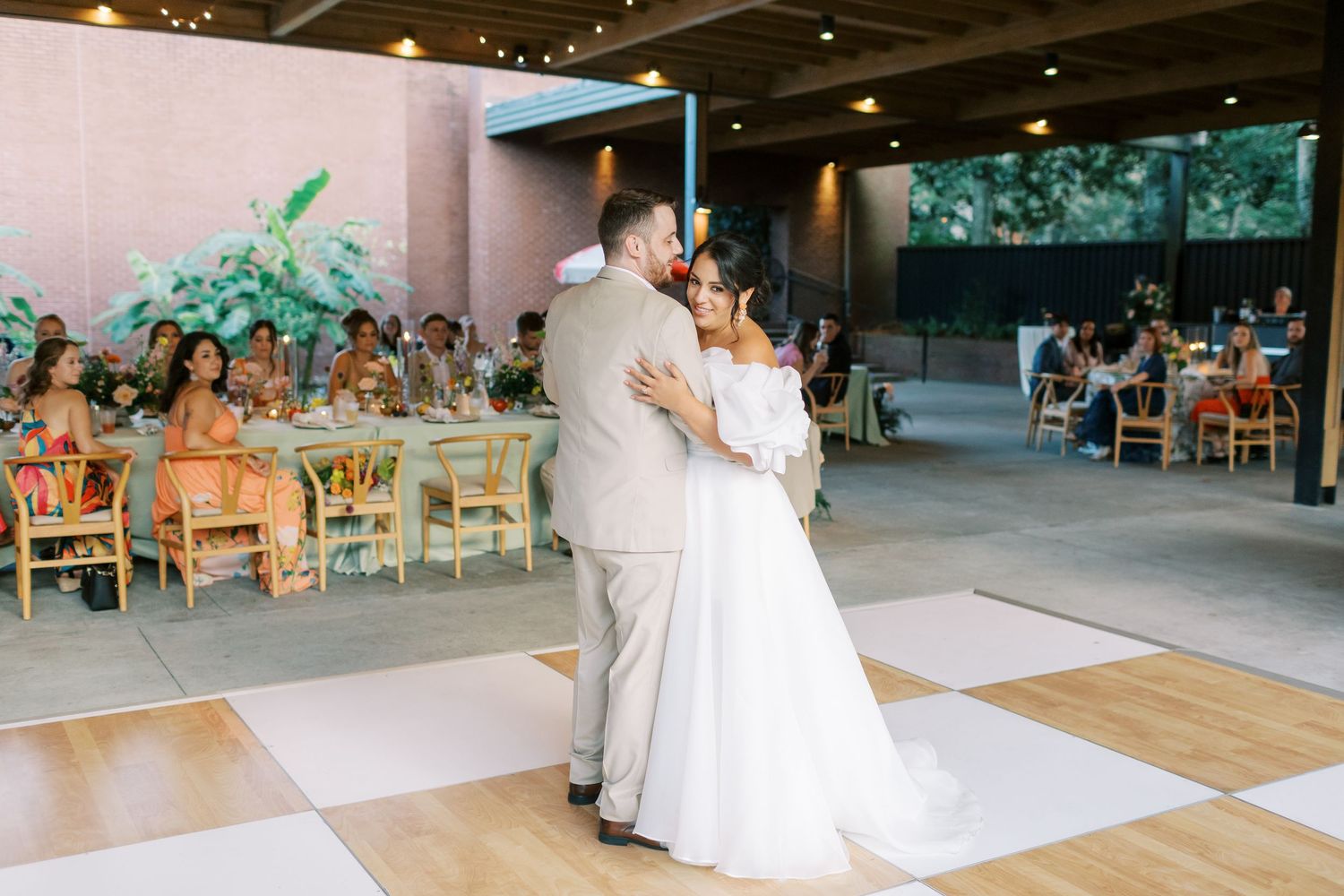 Light-filled wedding reception space with rows of decorated tables and chairs.