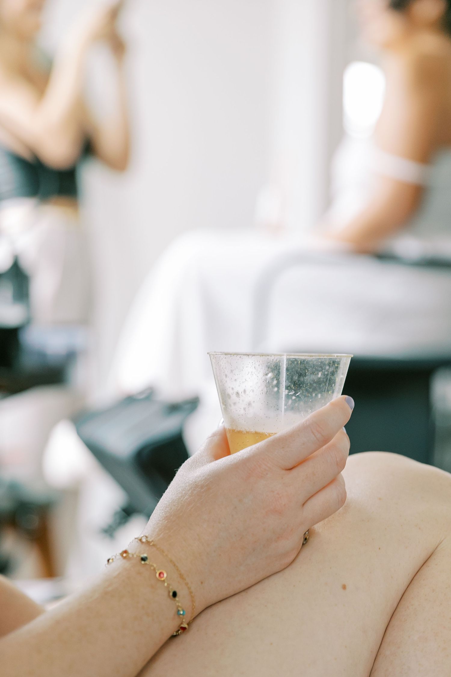 Crystal champagne glass sparkles against soft beige fabric background in minimalist wedding scene.