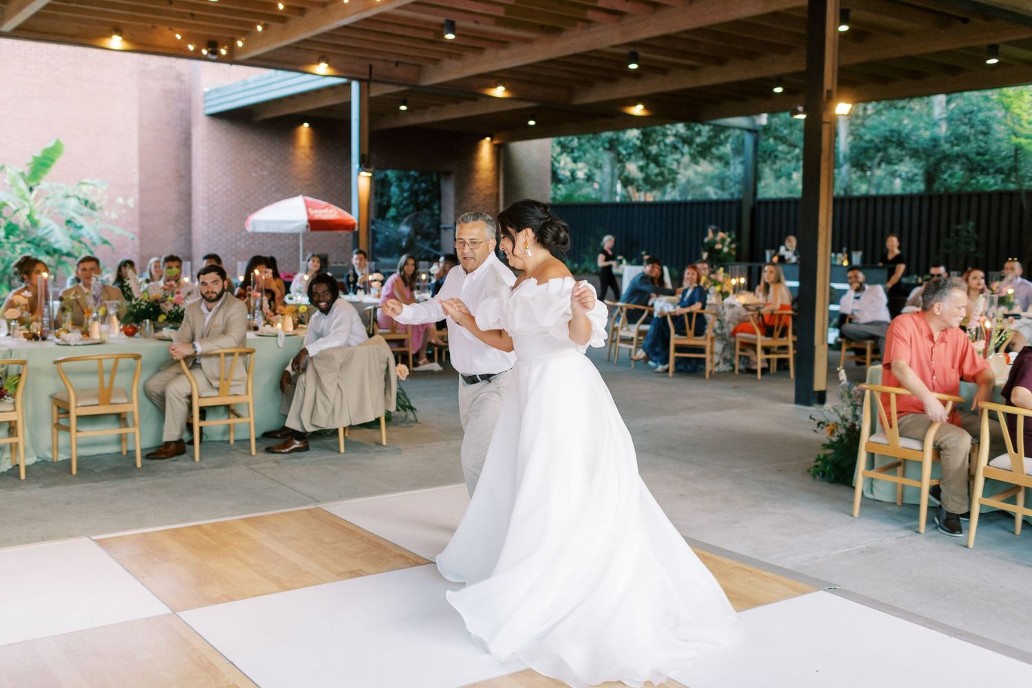 Wide shot of an outdoor wedding reception venue with guests dancing and dining.