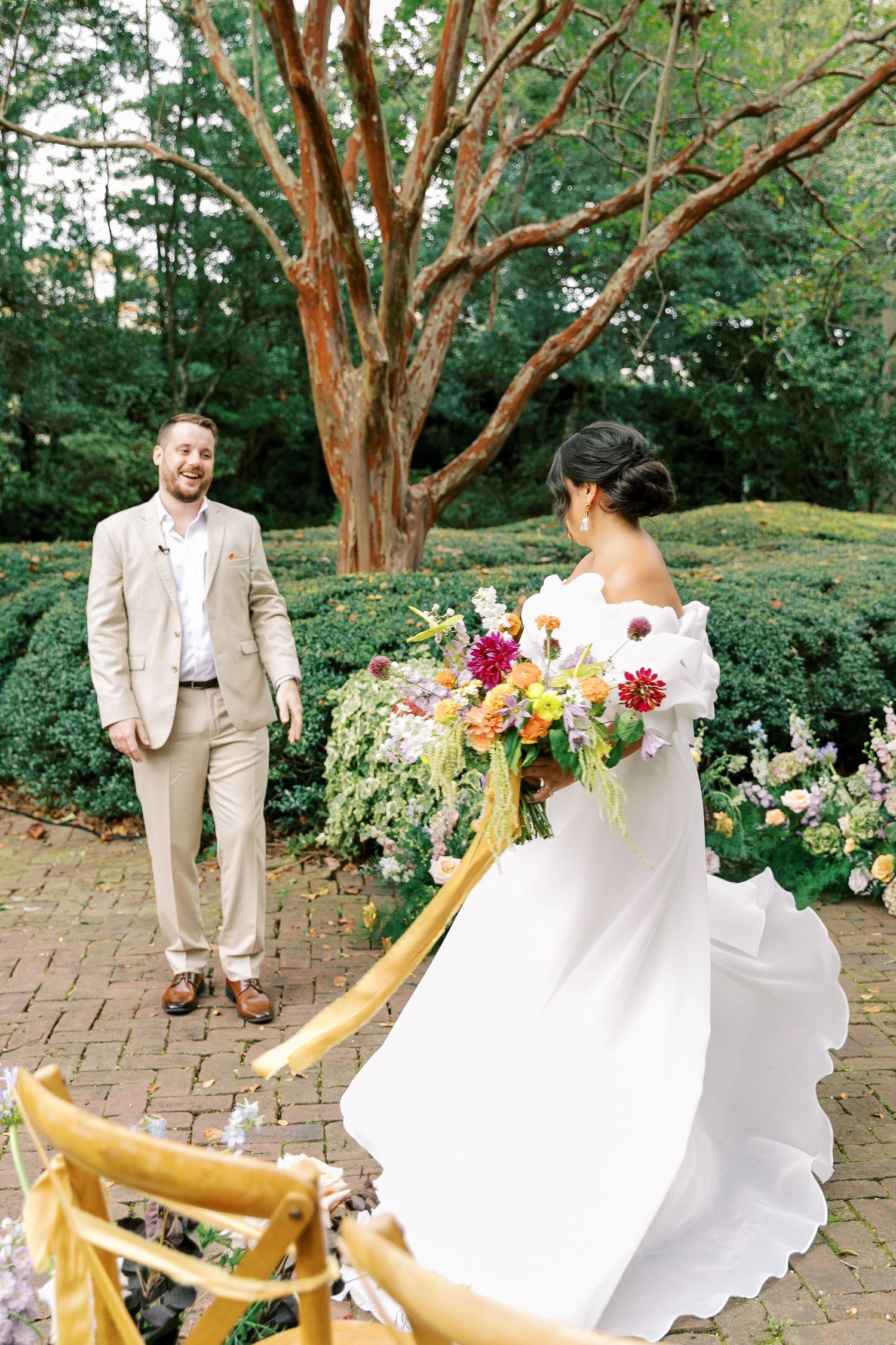 Dancing couple celebrates on brick patio surrounded by flowering gardens and trees.