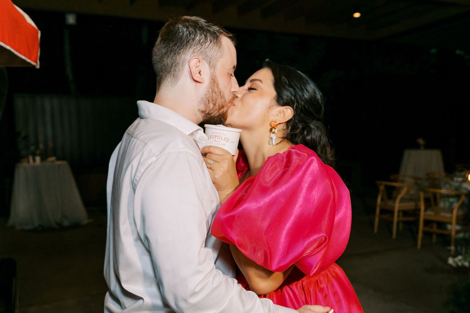A romantic moment shared during a wedding reception with bright pink formal attire.