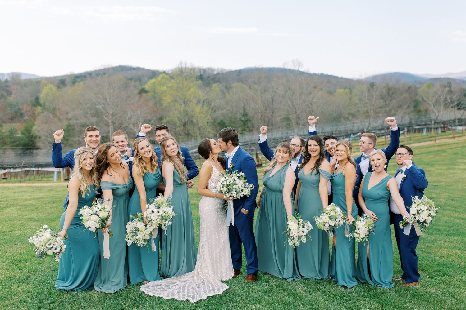 Wedding party poses together in teal bridesmaid dresses against rolling mountain landscape in North Georgia