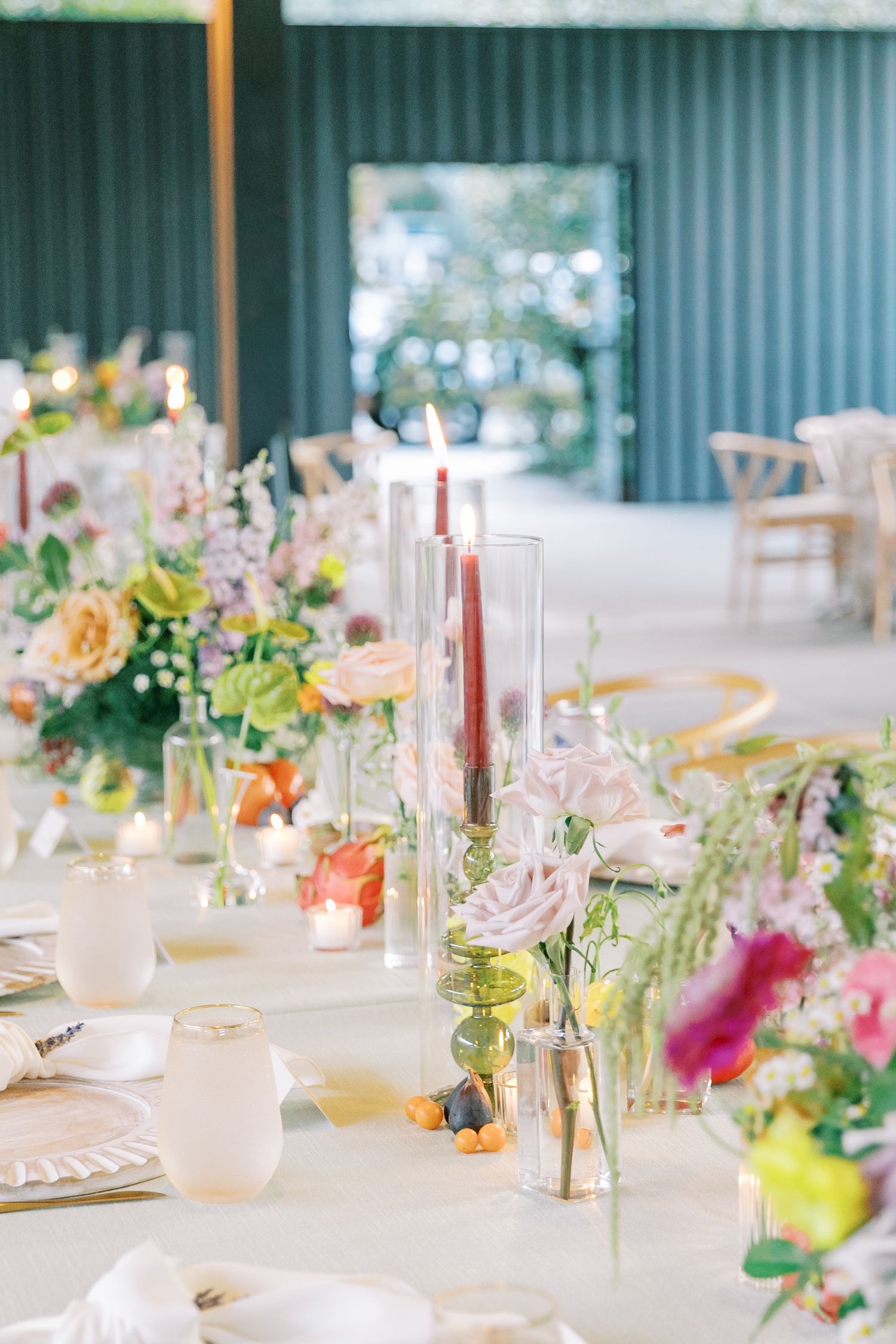 An elegant wedding reception table setting with colorful floral centerpieces and white linens.