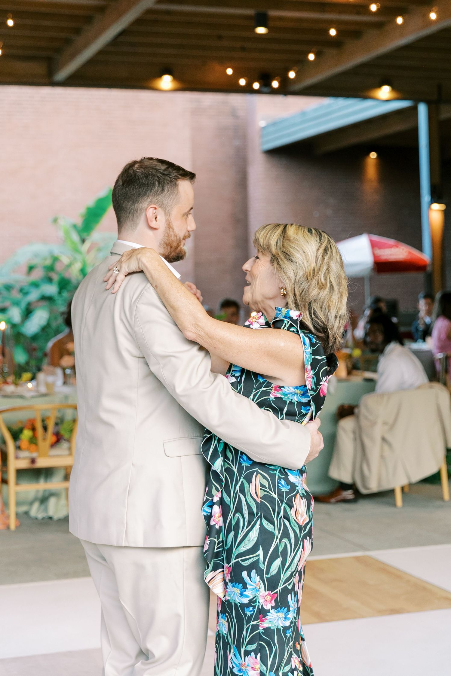 A couple shares a romantic dance moment at their wedding reception under string lights.