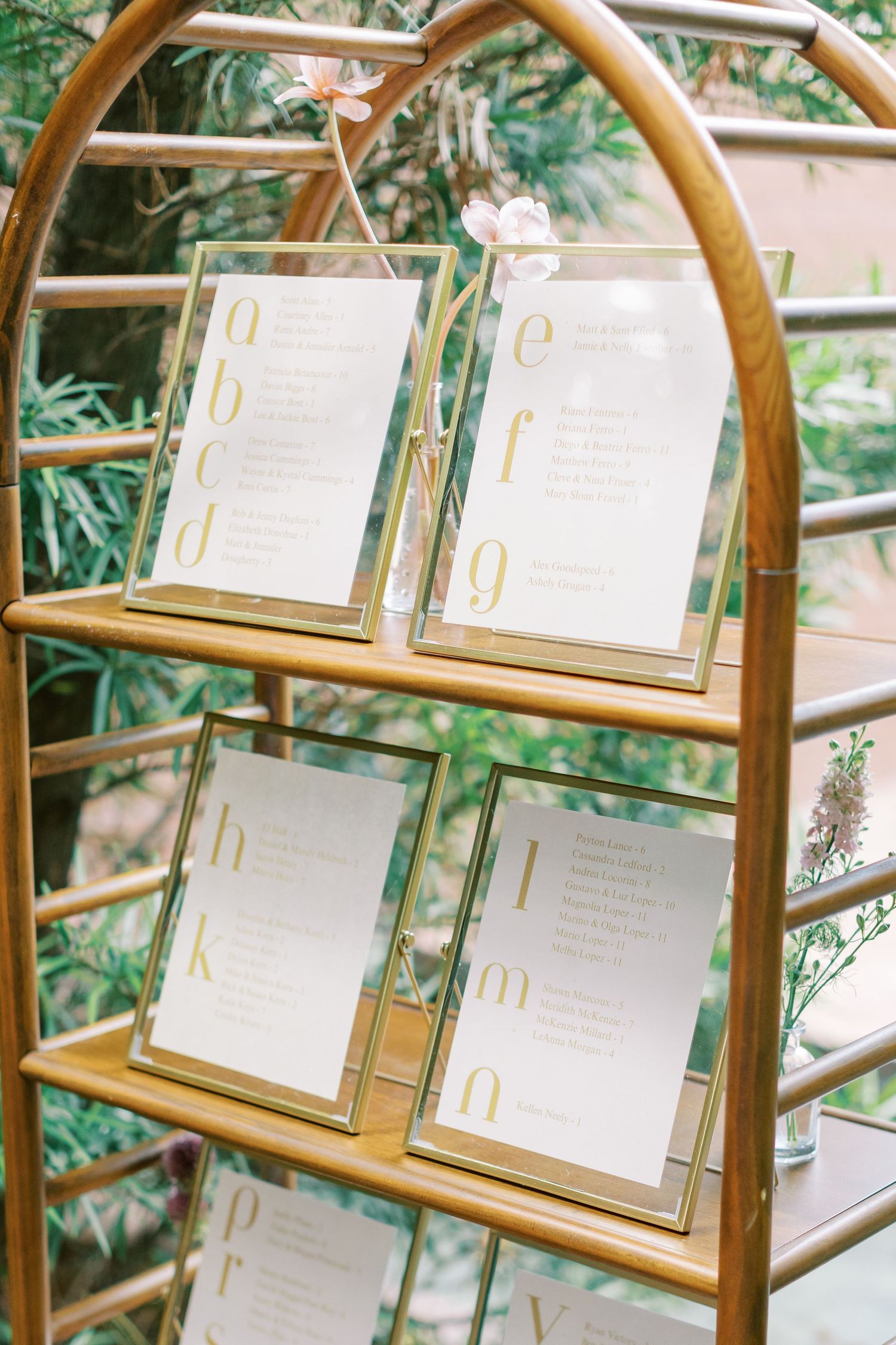 Wedding seating chart displayed on an elegant gold-framed stand with multiple frames.