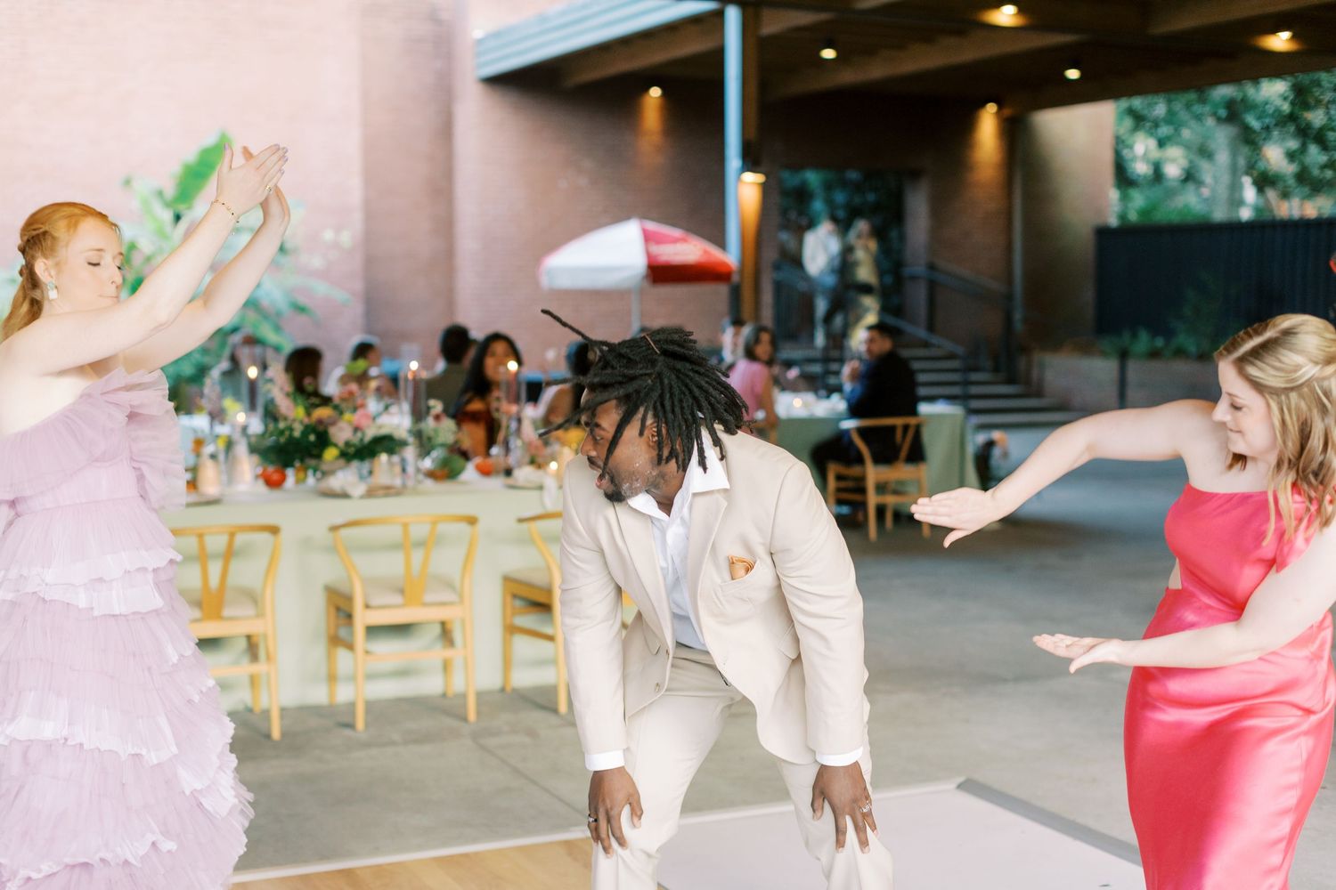 Wedding guests dancing and celebrating at an indoor reception venue.