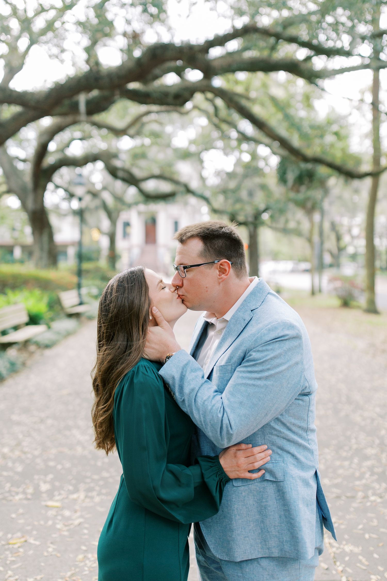 A romantic moment shared between a couple beneath moss-draped oak trees on a historic path.